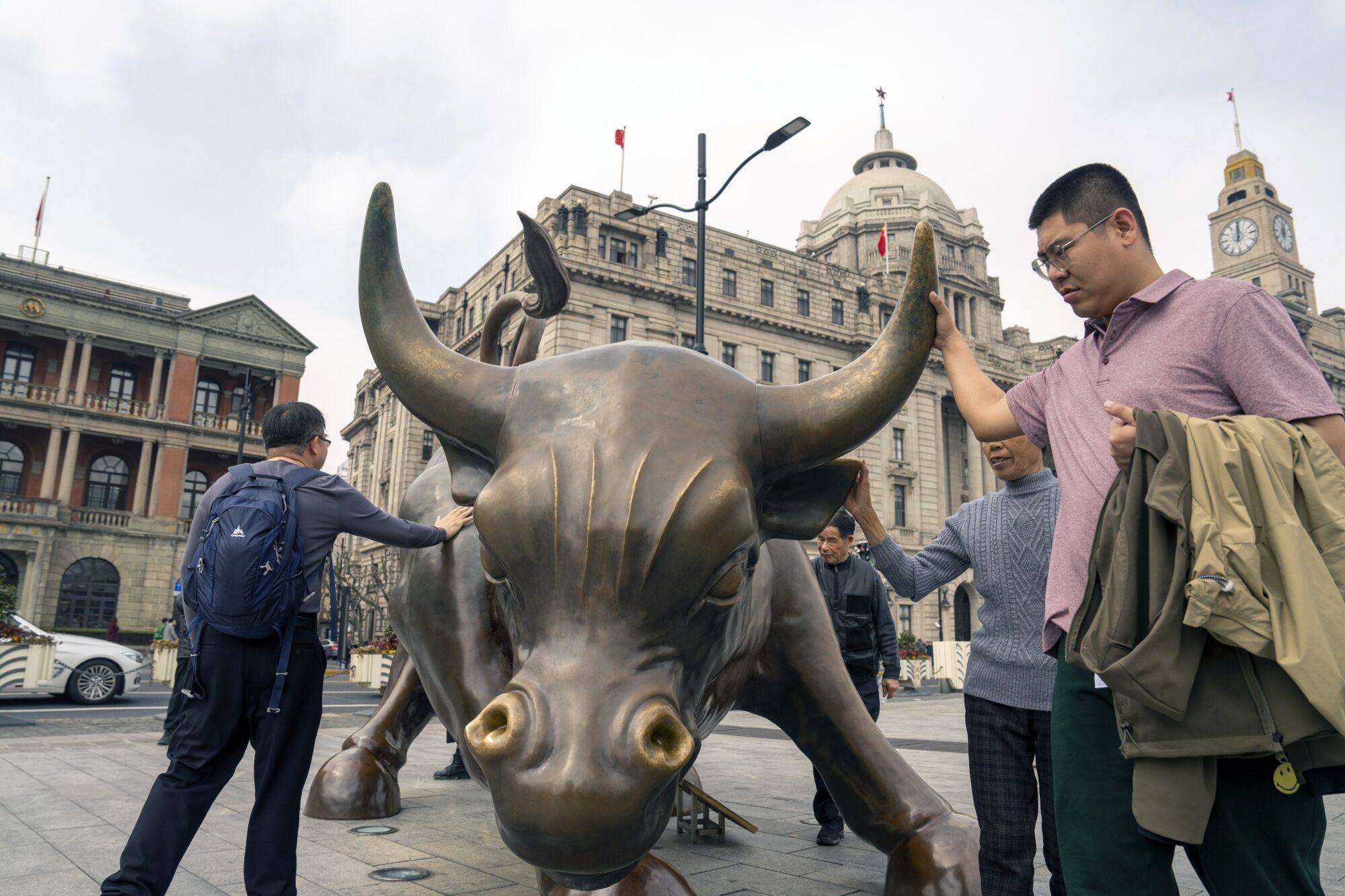 Pedestrians touch the Bund Bull in Shanghai on February 19, 2024. Photo: Bloomberg
