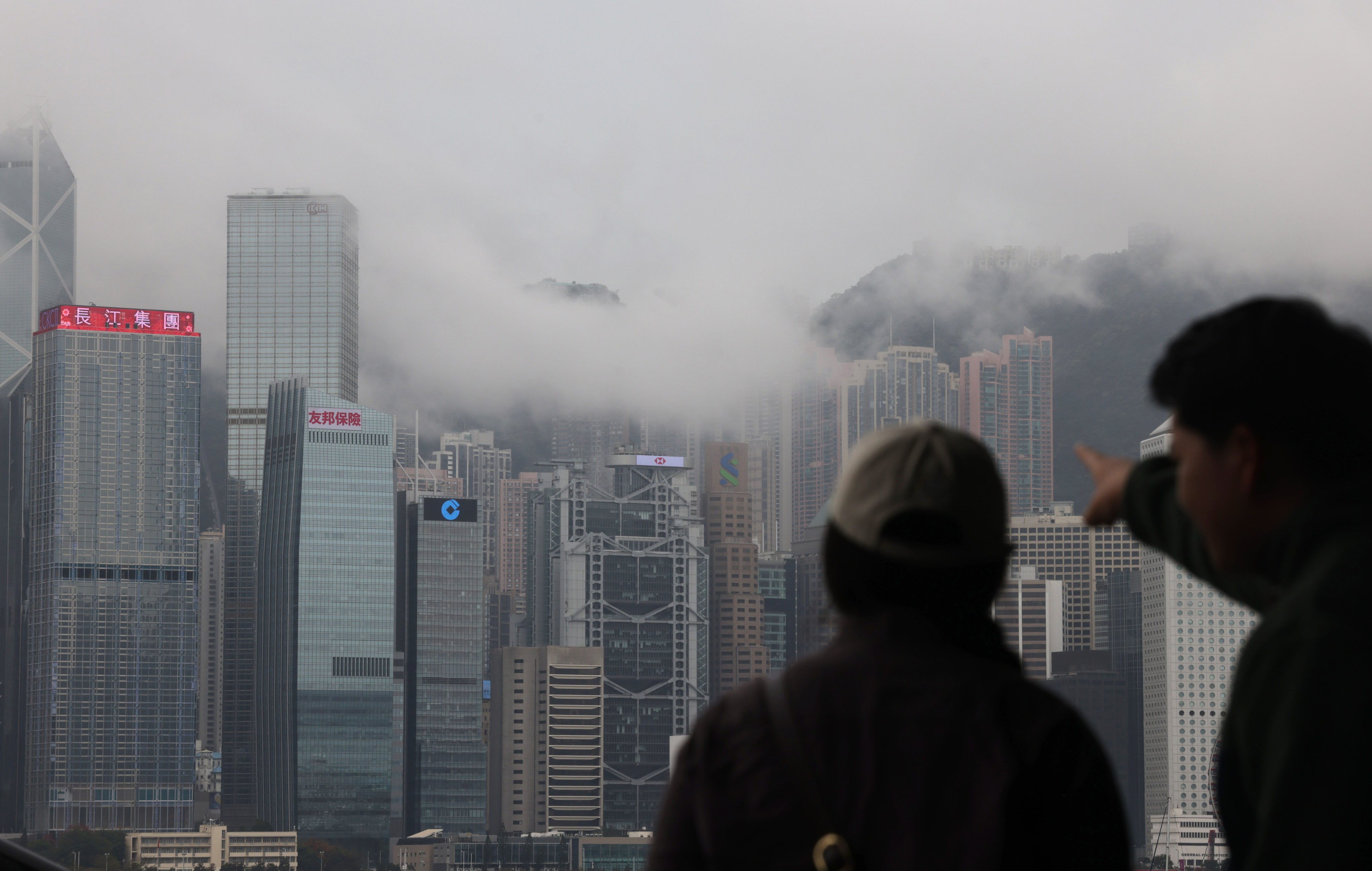 People on the Tsim Sha Tsui waterfront point to fog covering Hong Kong’s iconic skyline on March 11. Photo: Jelly Tse