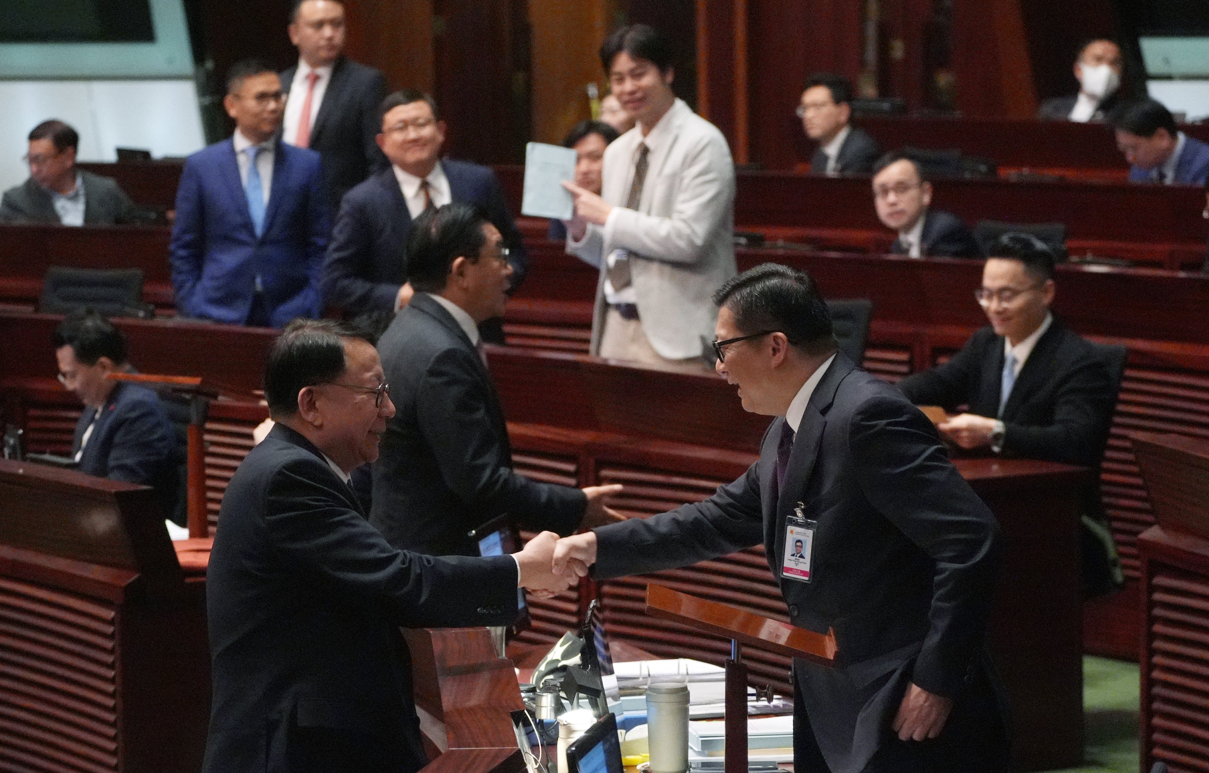 Chief Secretary for Administration Eric Chan Kwok-ki (L) shakes hand with Secretary for Justice Chris Tang Ping-kwung after  Basic Law Article 23 legislation at Legislative Council is passed. Photo: Eugene Lee