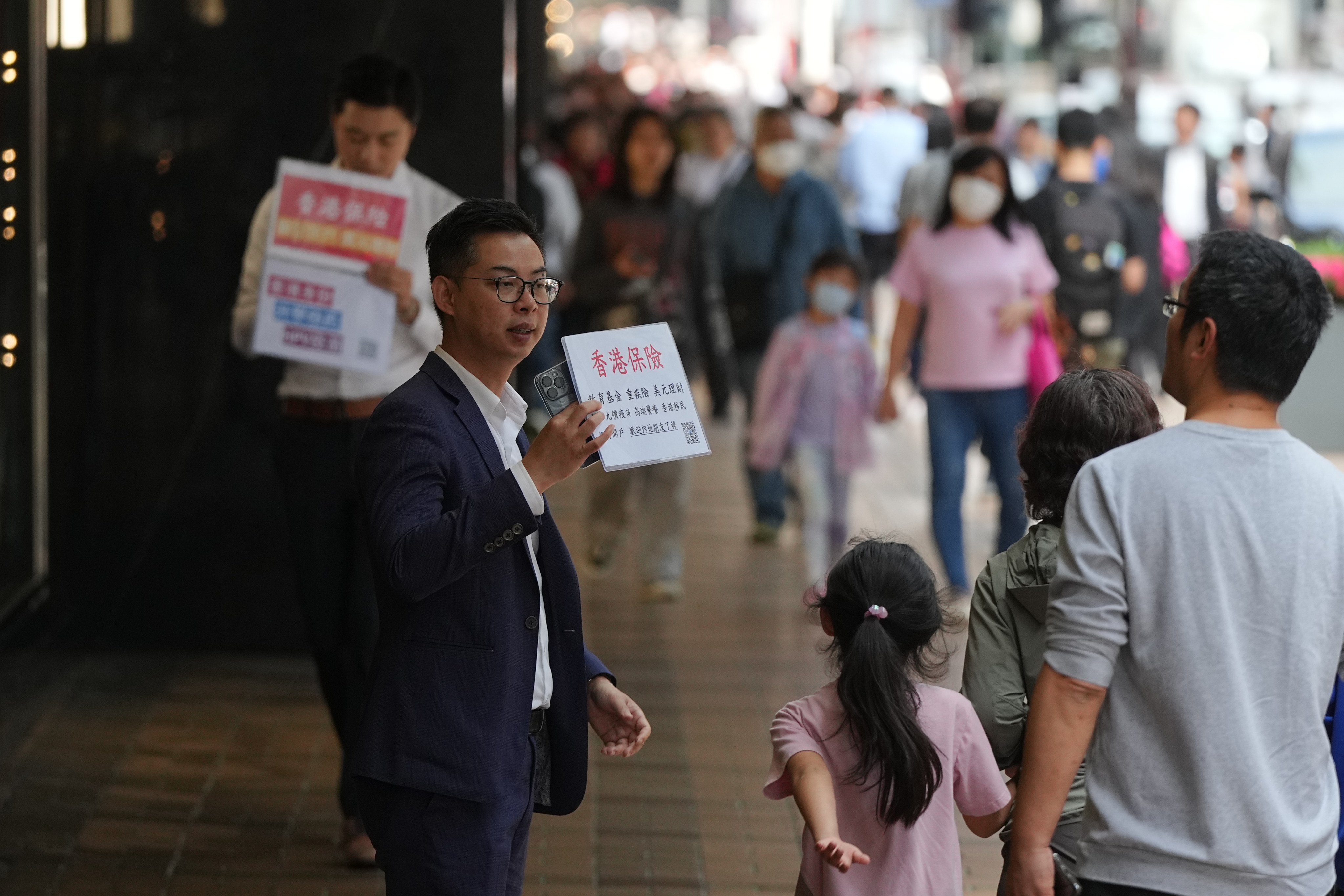 An insurance salesman approaches mainland Chinese tourists in Tsim Sha Tsui, Hong Kong. Photo: Eugene Lee