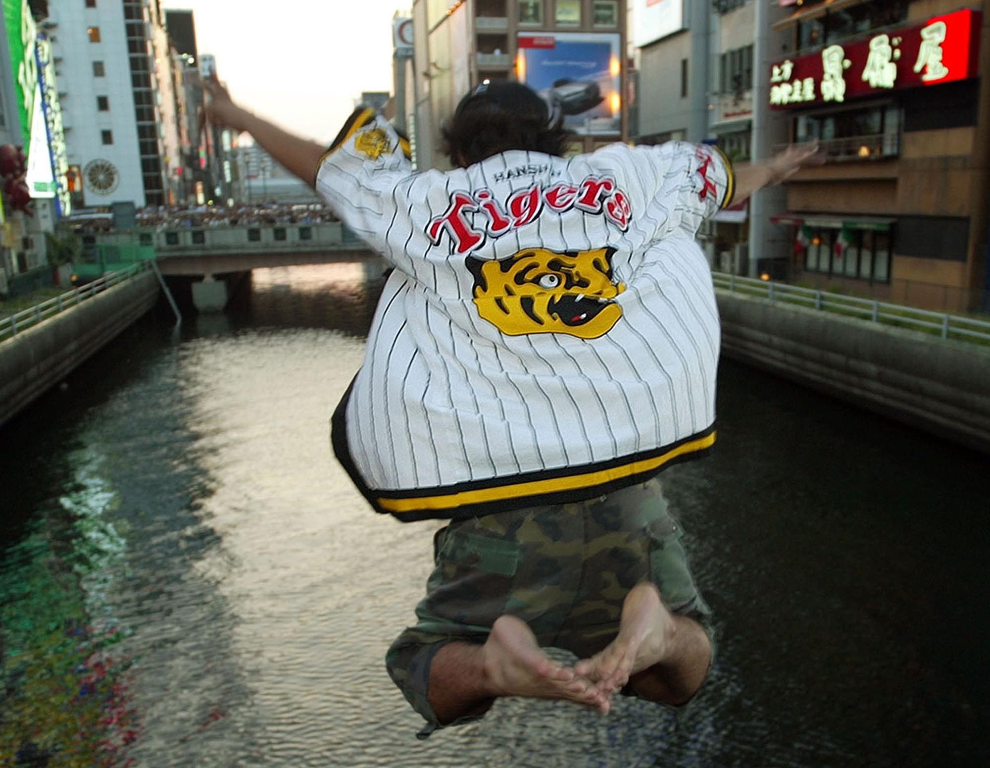 An enthusiastic fan of the Hanshin Tigers dives into Dotonbori River in Osaka, western Japan, on September 15, 2003. Photo: AP