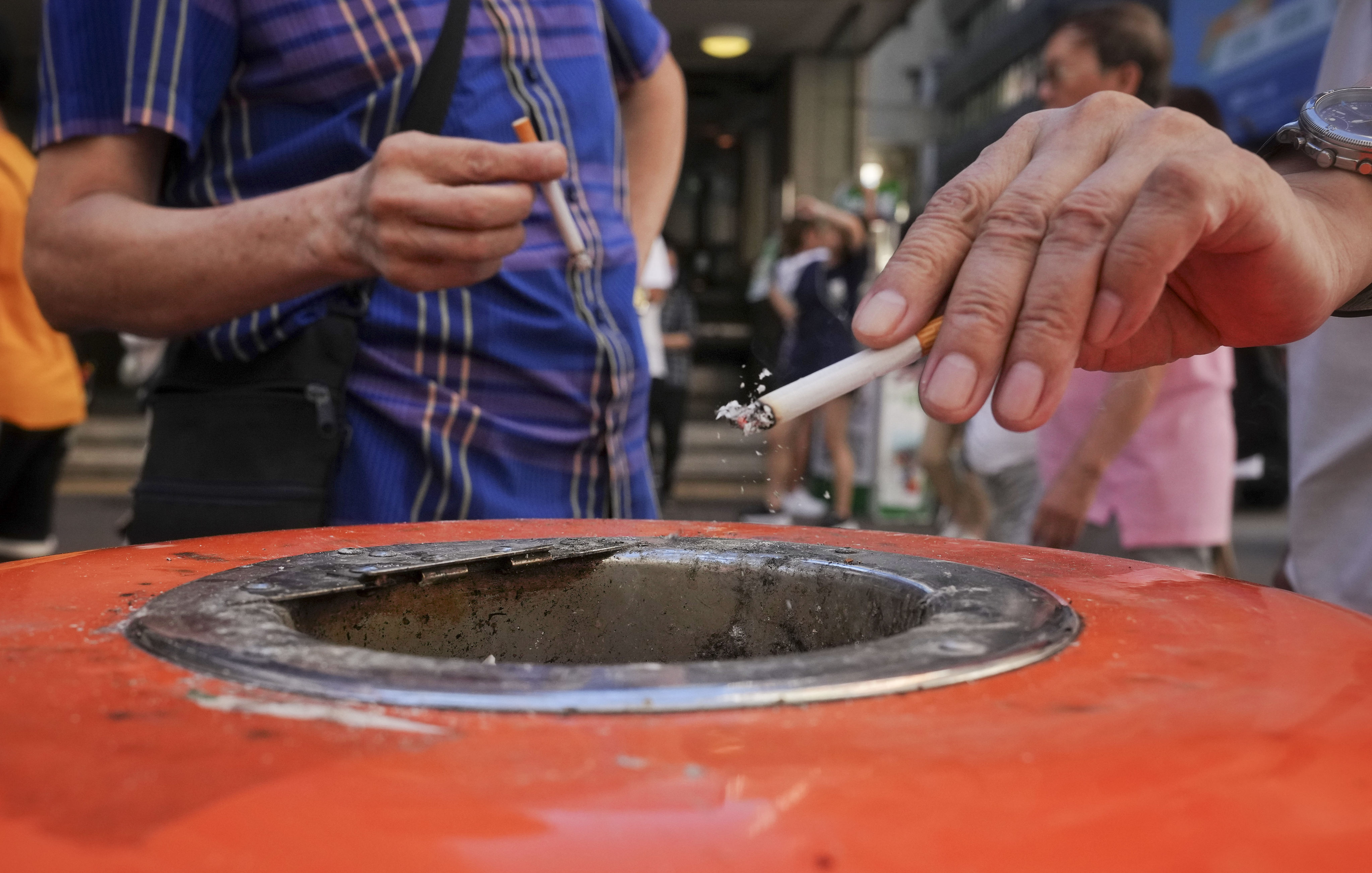Smokers place their cigarette butts inside a rubbish bin in Wan Chai in July 2023. Photo: Elson Li