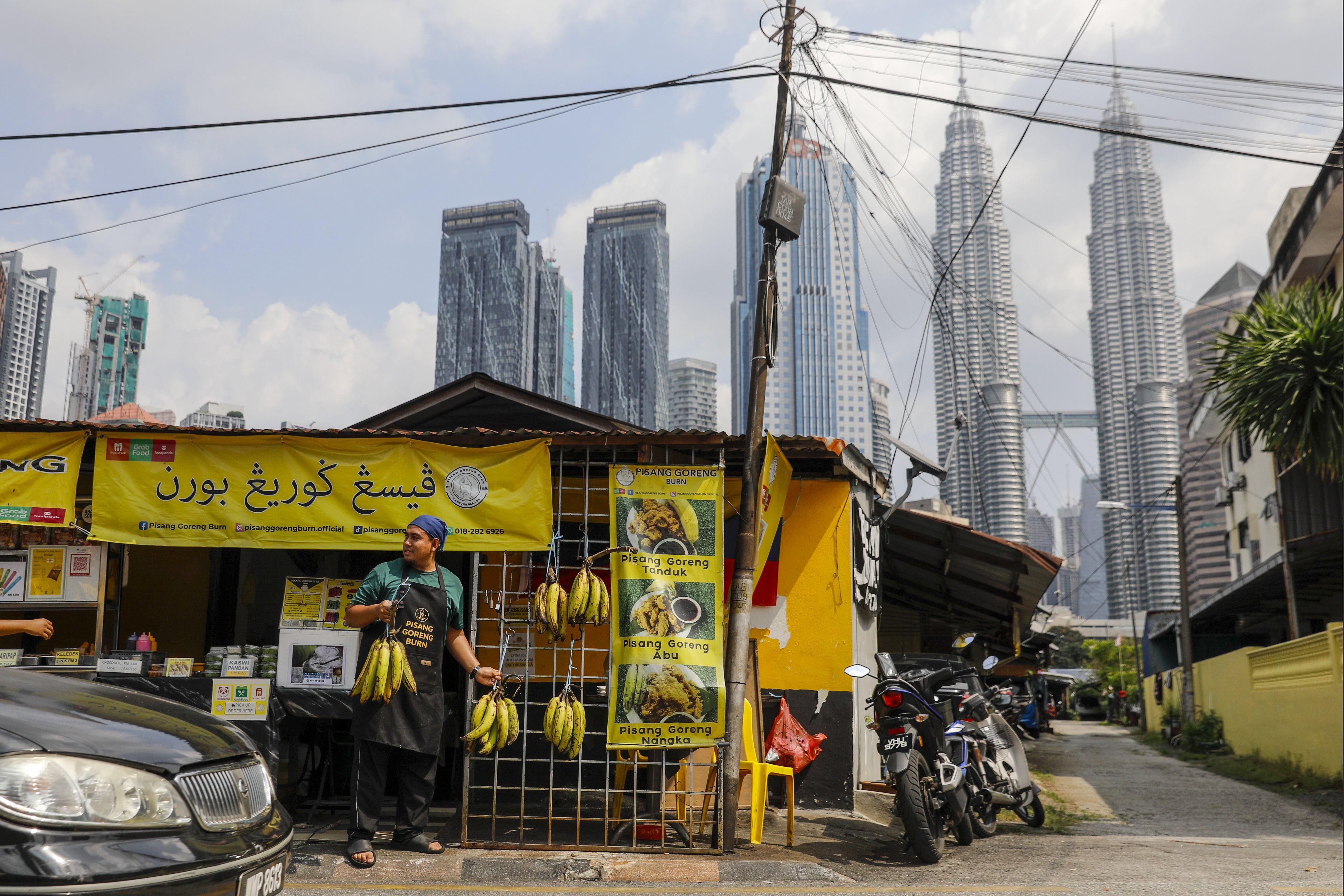A man displays bananas outside his shop with the Malaysia’s iconic Petronas Twin Tower in the background in Kuala Lumpur. The Home Ministry had initially planned to present a bill on the matter to parliament once it gained the cabinet’s approval. Photo: EPA-EFE