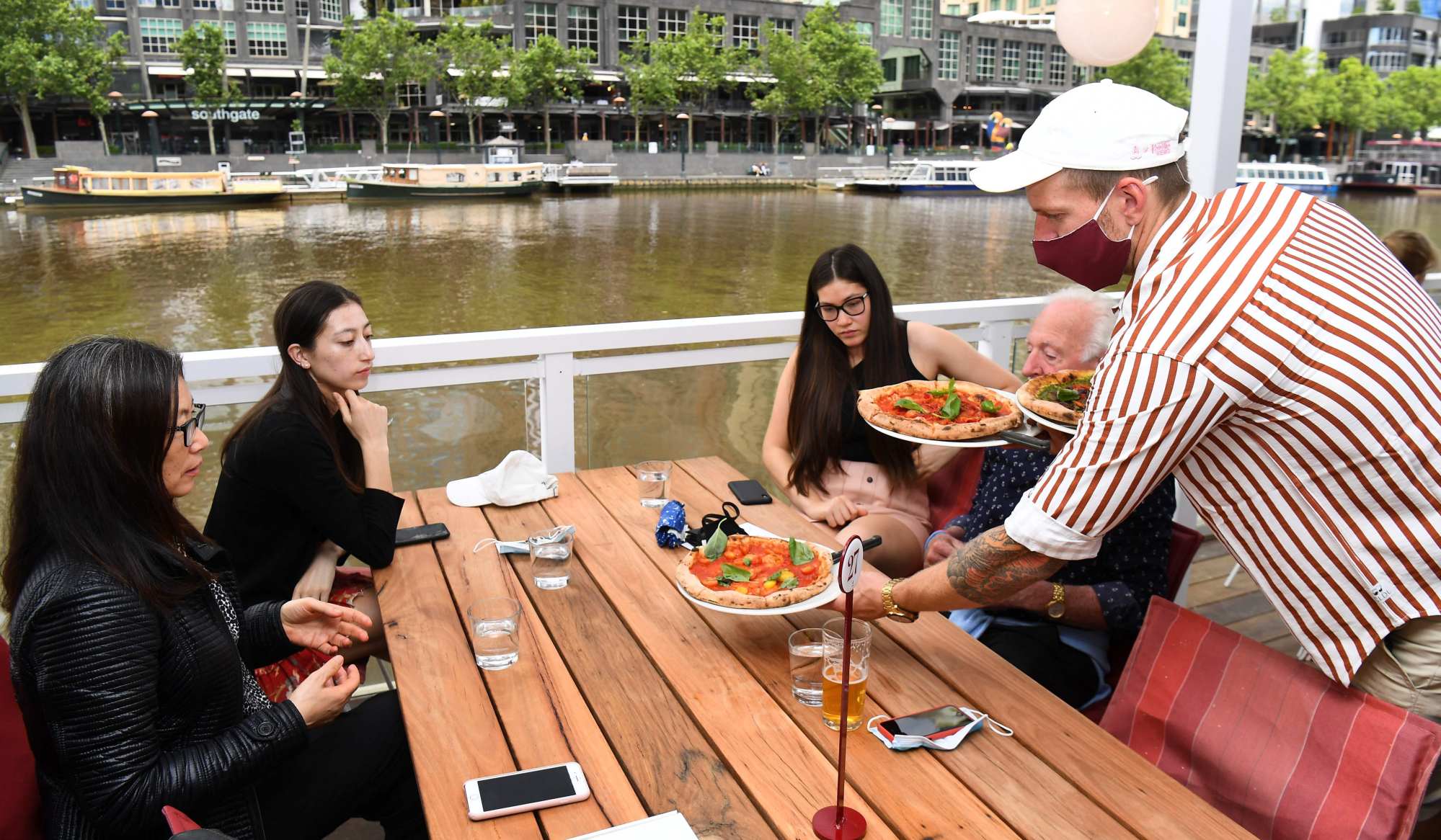 People have a meal at a cafe on Melbourne’s Yarra River. According to global booking service OpenTable, the number of seated diners in Australia dropped every month this year compared with last year. Photo: AFP