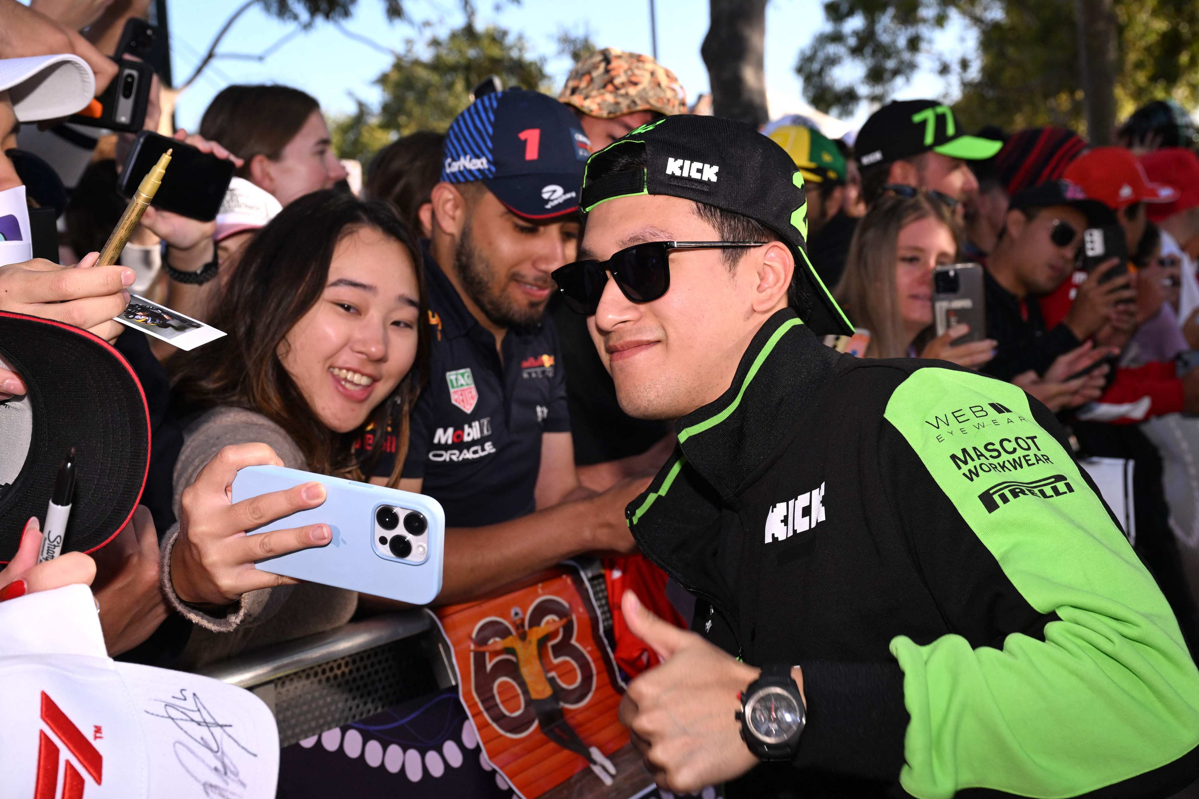 Kick Sauber’s Chinese driver Zhou Guanyu poses for a selfie with a fan on the Melbourne Walk ahead of the Australian Grand Prix in Melbourne. Photo: AFP