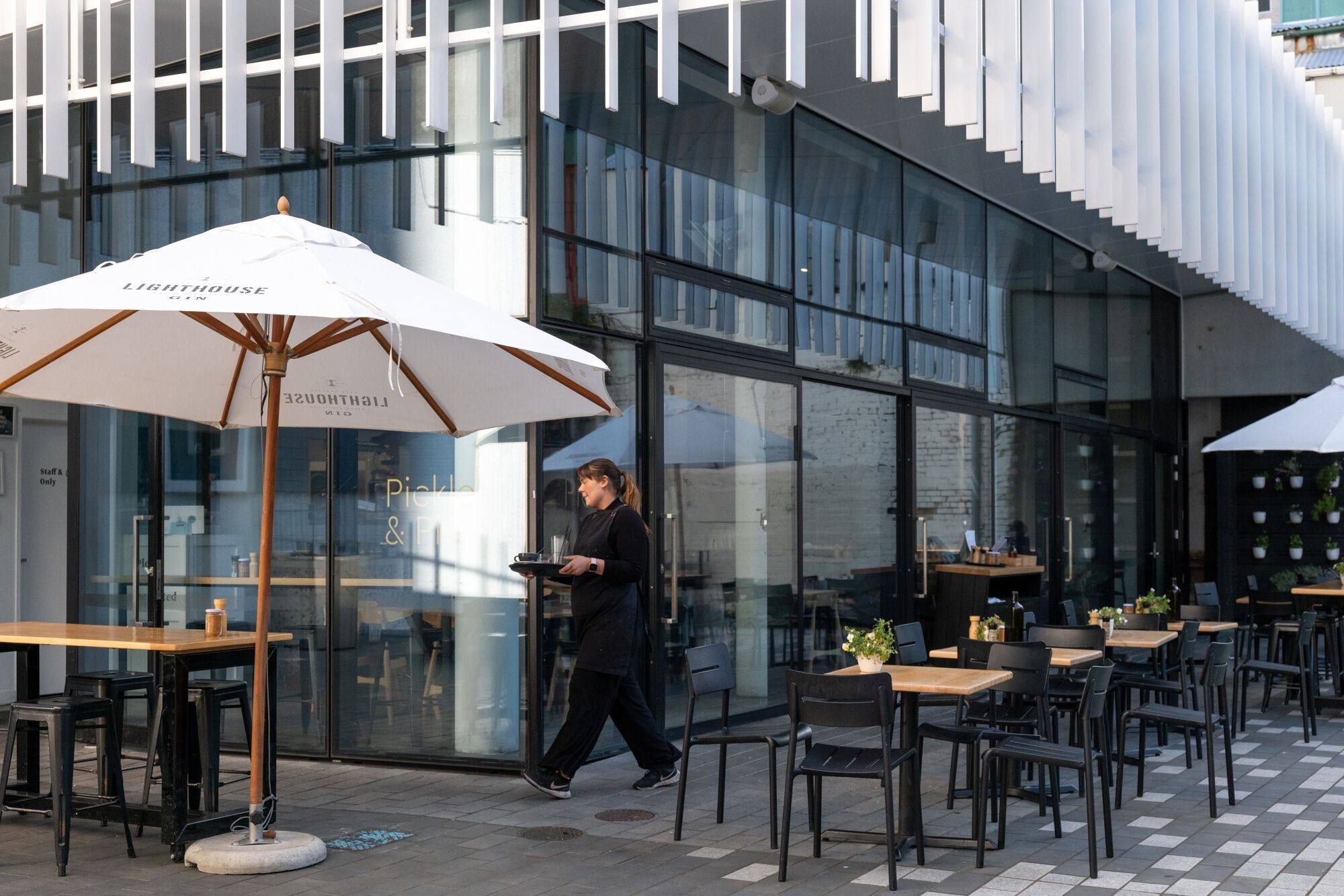 A waitress clears up outdoor tables of a restaurant in Wellington, New Zealand, in August last year. Photo: Bloomberg