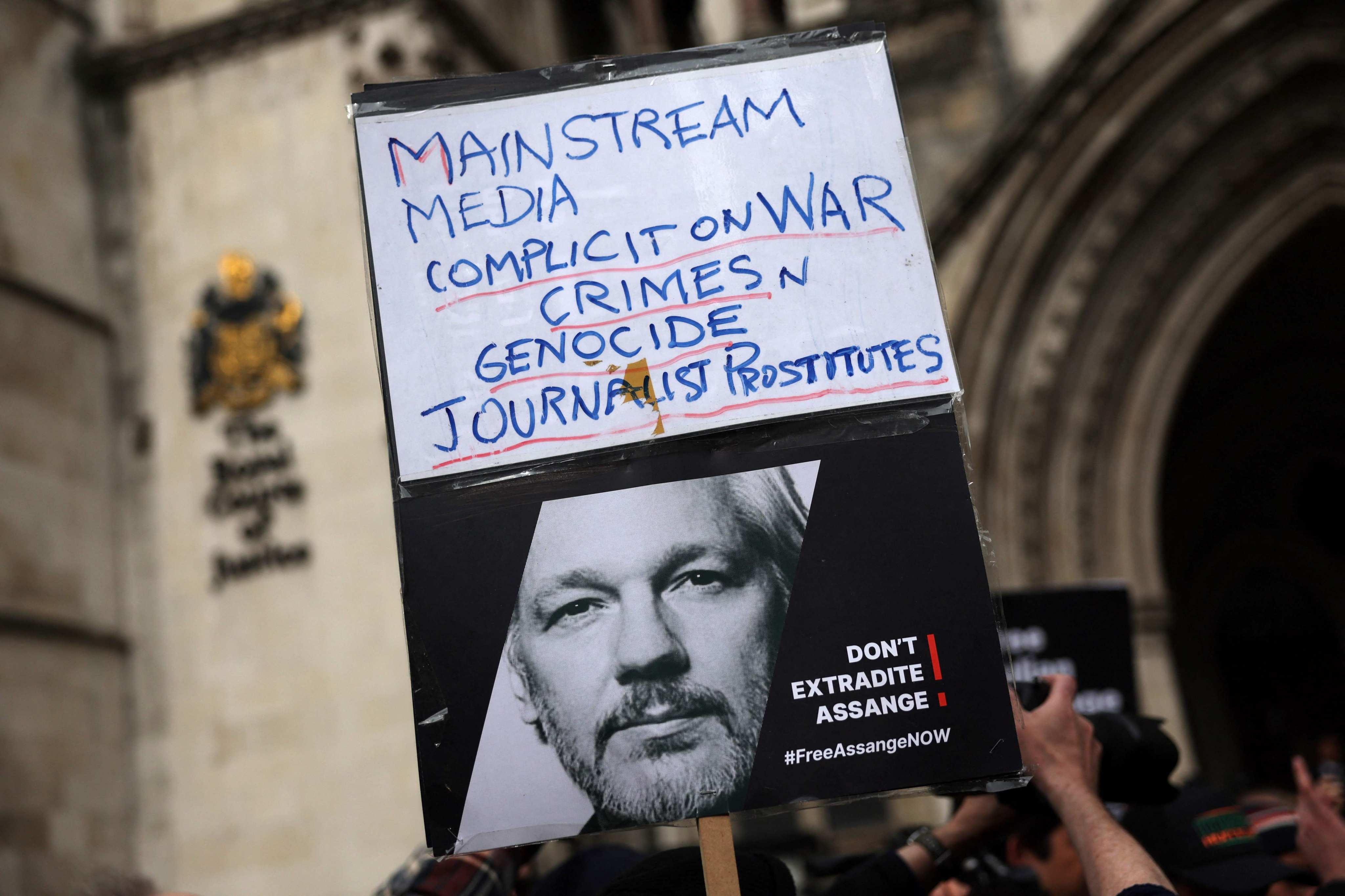A supporter of WikiLeaks founder Julian Assange holds a placard outside The Royal Courts of Justice in London Tuesday. Photo: AFP