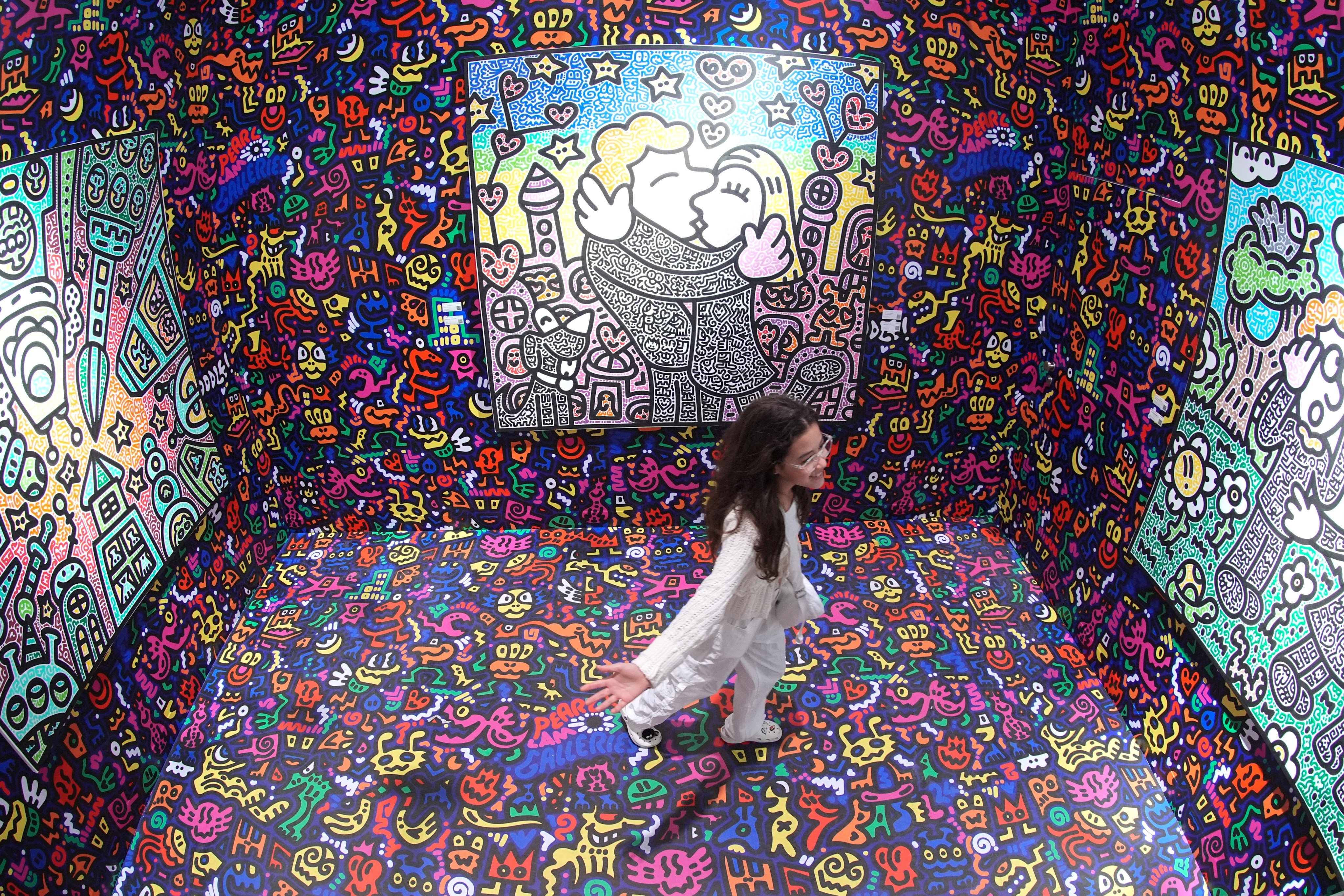 A visitor poses for a photo next to the artwork titled “Mas jumps in his Vortex to DoodleLand” by Mr Doodle. Photo: Eugene Lee
