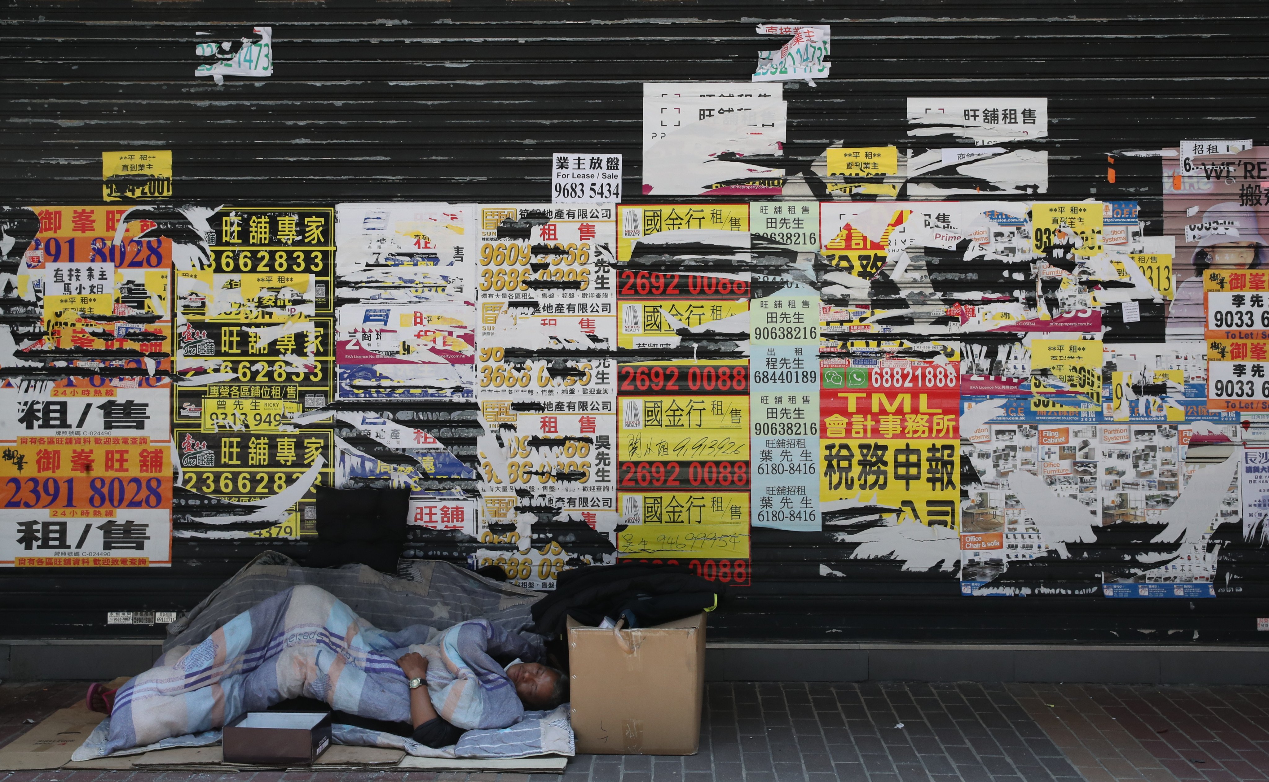 A homeless man sleeps in front of a shuttered shop in Mong Kok in April 2022. Photo: Edmond So