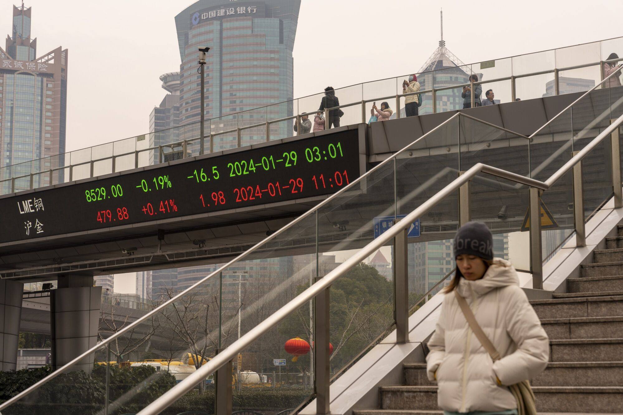 An electronic ticker displays stock figures in Shanghai’s Lujiazui financial district. Overseas investors continue to raise their holdings in banks and food and beverage makers, while cutting exposure to computer-linked stocks. Photo: Bloomberg