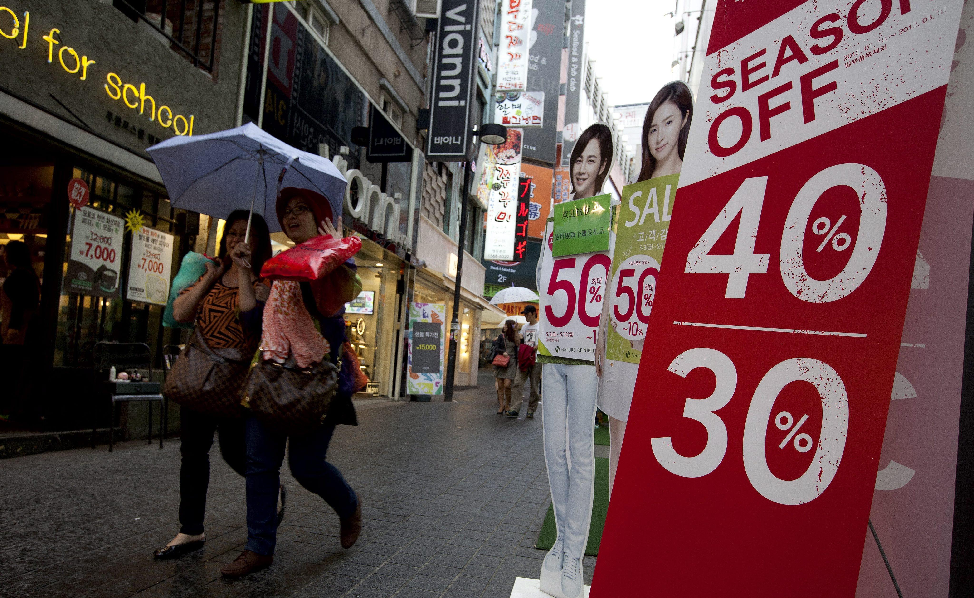 South Korean people pass a store advertising discount sales in Seoul, South Korea. Photo: EPA/File