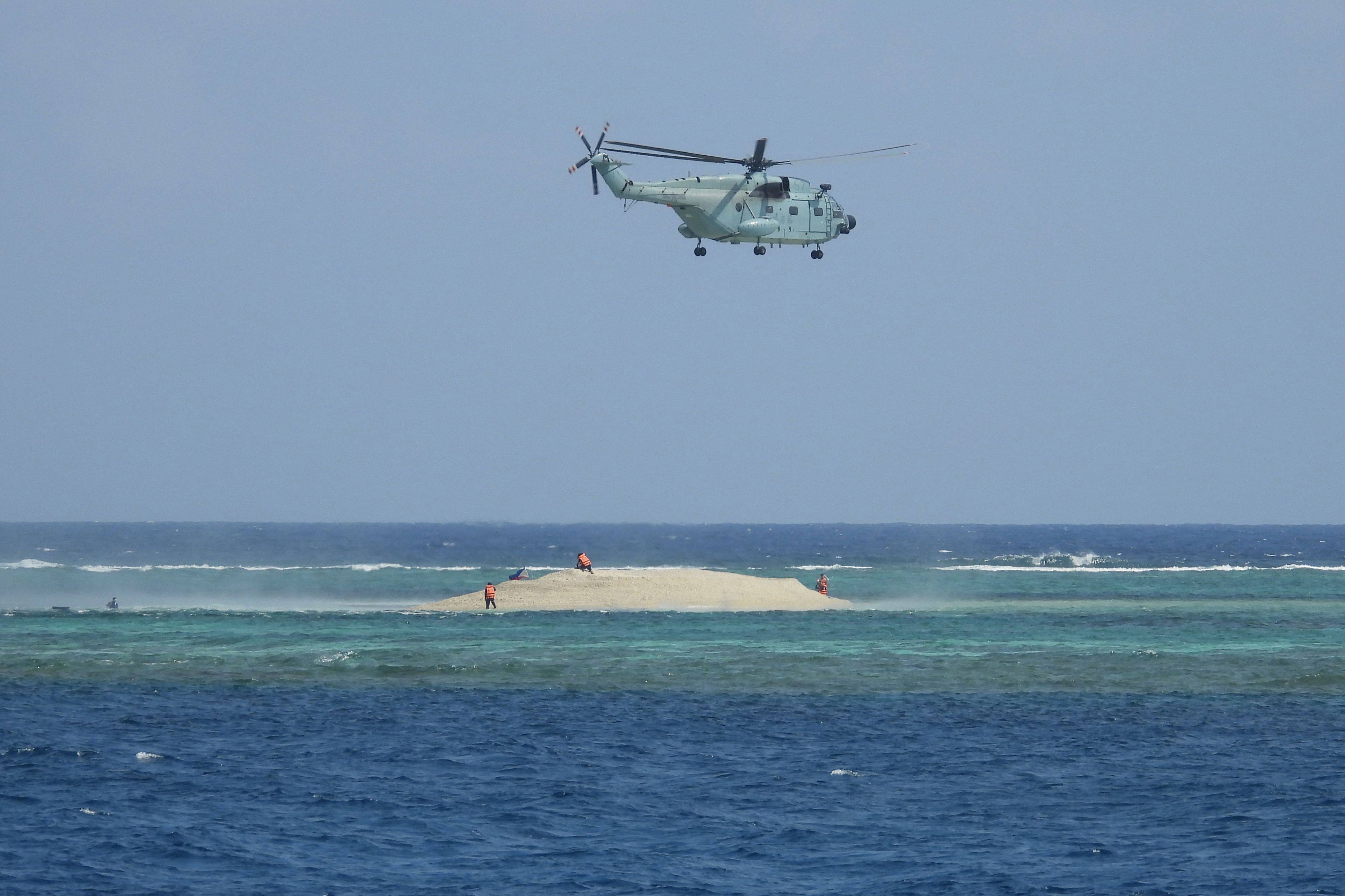 A Chinese helicopter hovers as Philippine scientists inspect a cay near the Thitu Island in the disputed South China Sea on March 23. Photo: PCG/AFP
