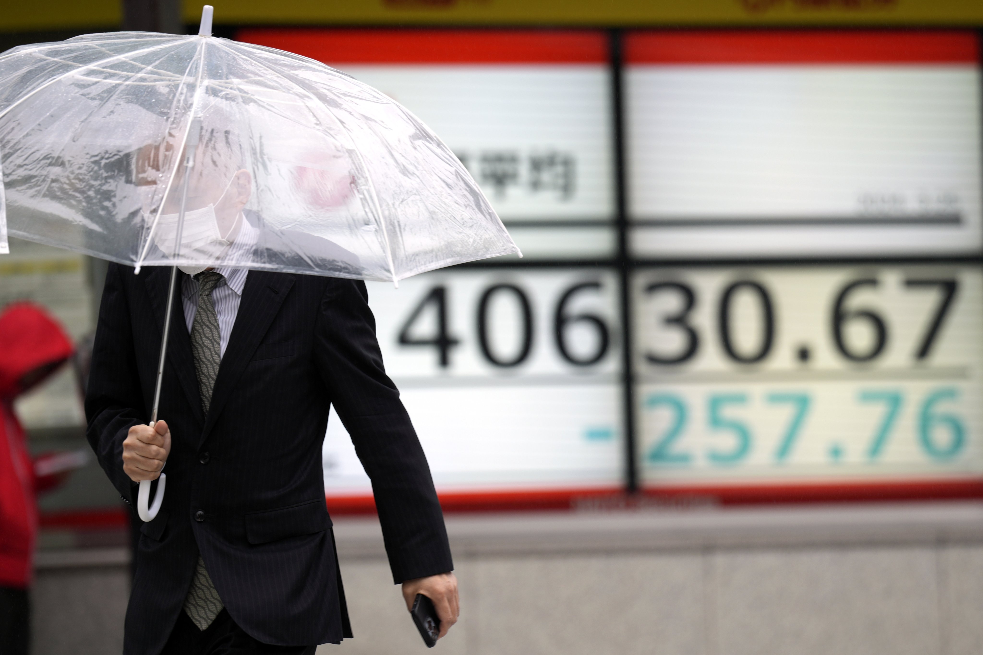 A person walks in front of an electronic stock board showing Japan’s Nikkei 225 index at a securities firm in Tokyo on March 25. Banks and other lenders are clamouring for an early cut in recently raised rates by the US Federal Reserve, the European Central Bank and others. The Bank of Japan is an exception. Photo: AP