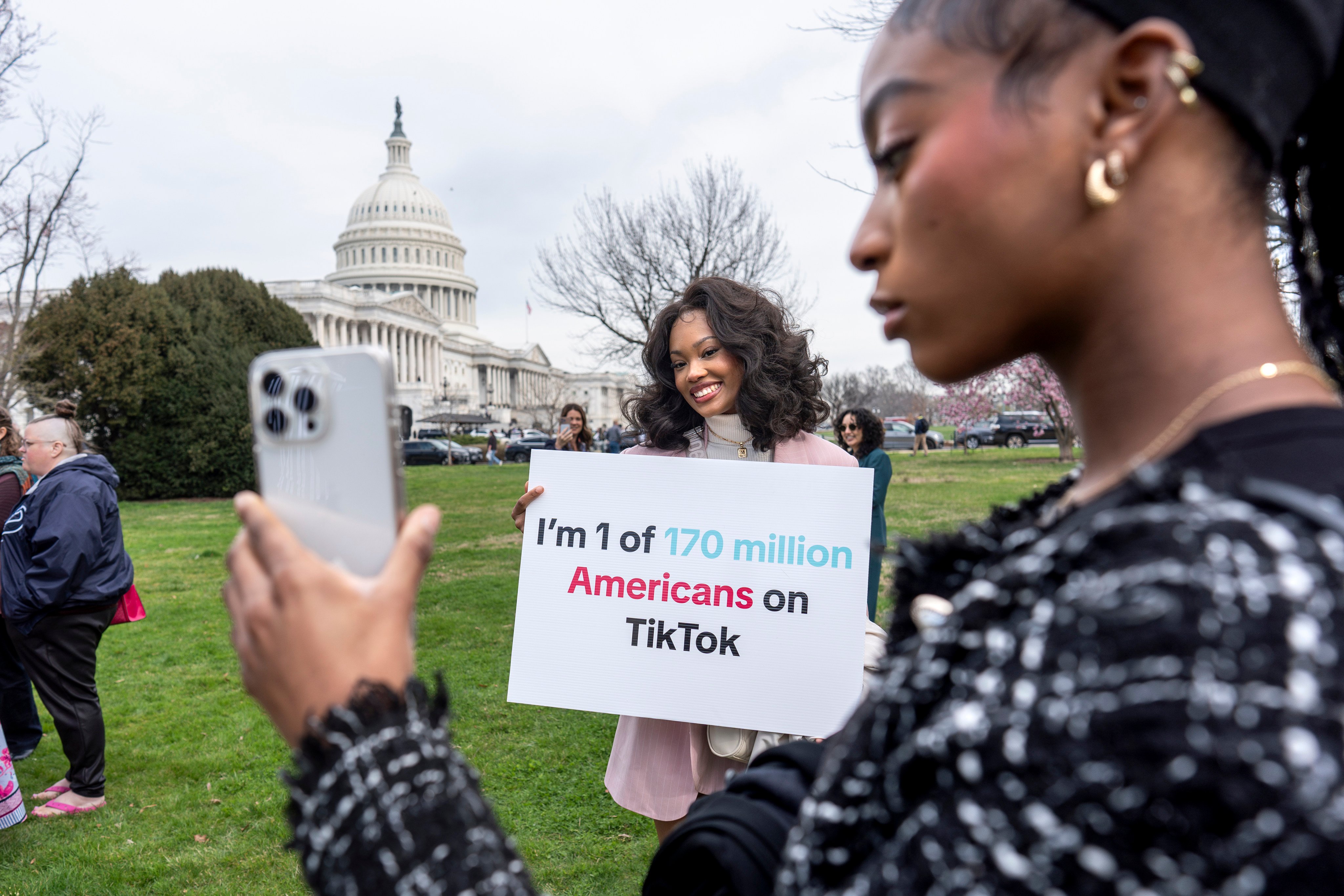 Two devotees of TikTok, Mona Swain (centre) and her sister  Rachel Swain (right), pose with a sign expressing their support at the US Capitol on March 13. Photo: AP