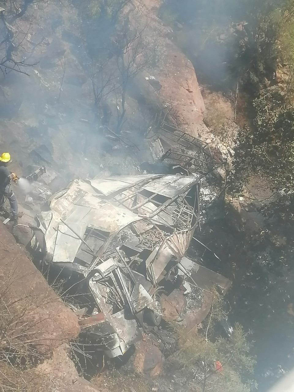 Firefighters hose down the wreckage of a bus after it crashed in Limpopo Province, South Africa on Thursday. Photo:   Limpopo Department of Transport and Community Safety via Reuters