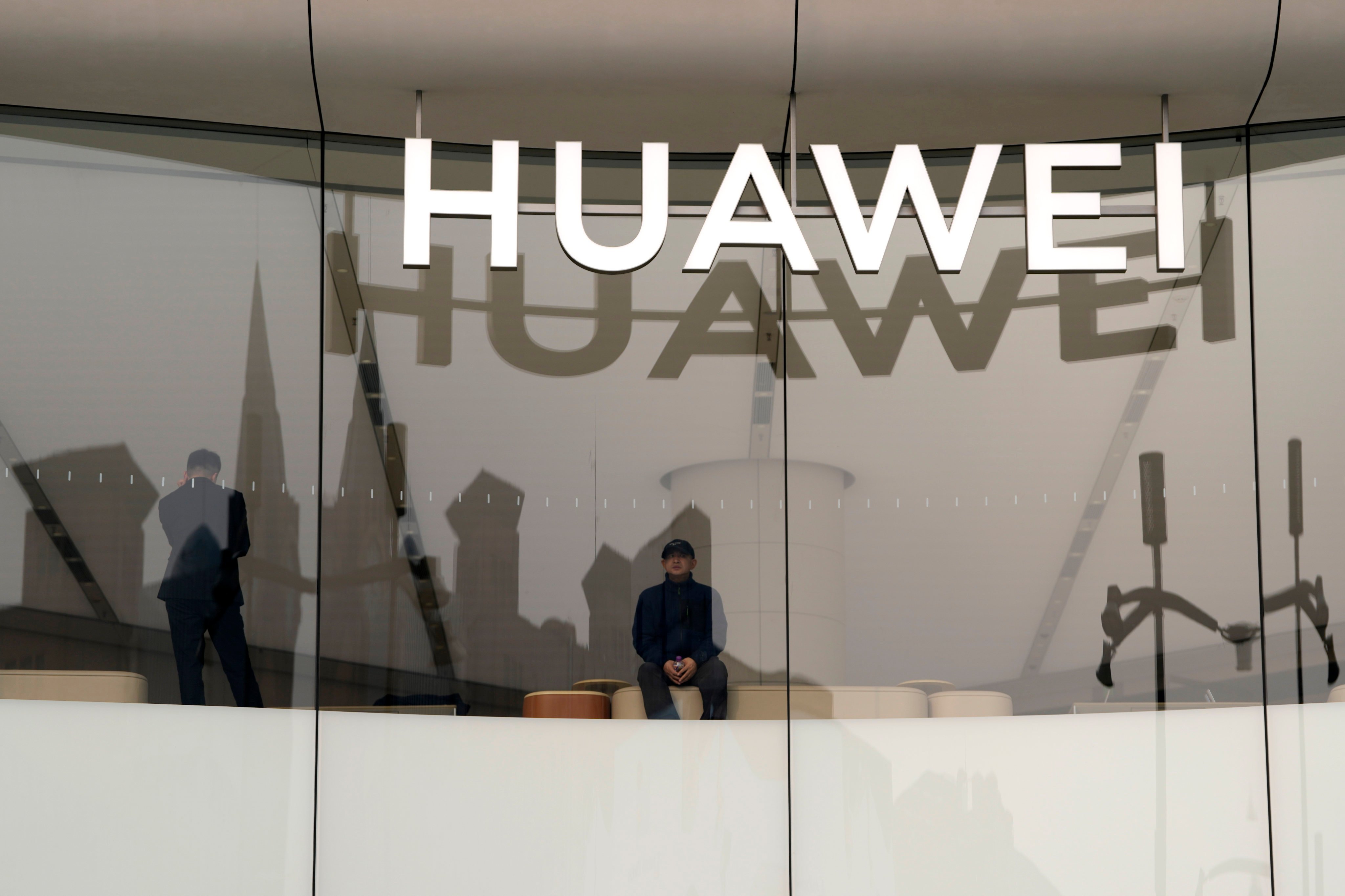 A visitor to the Huawei store in Beijing looks out the window near the logo for the Chinese telecommunications equipment giant on March 26, 2024. Photo: AP 