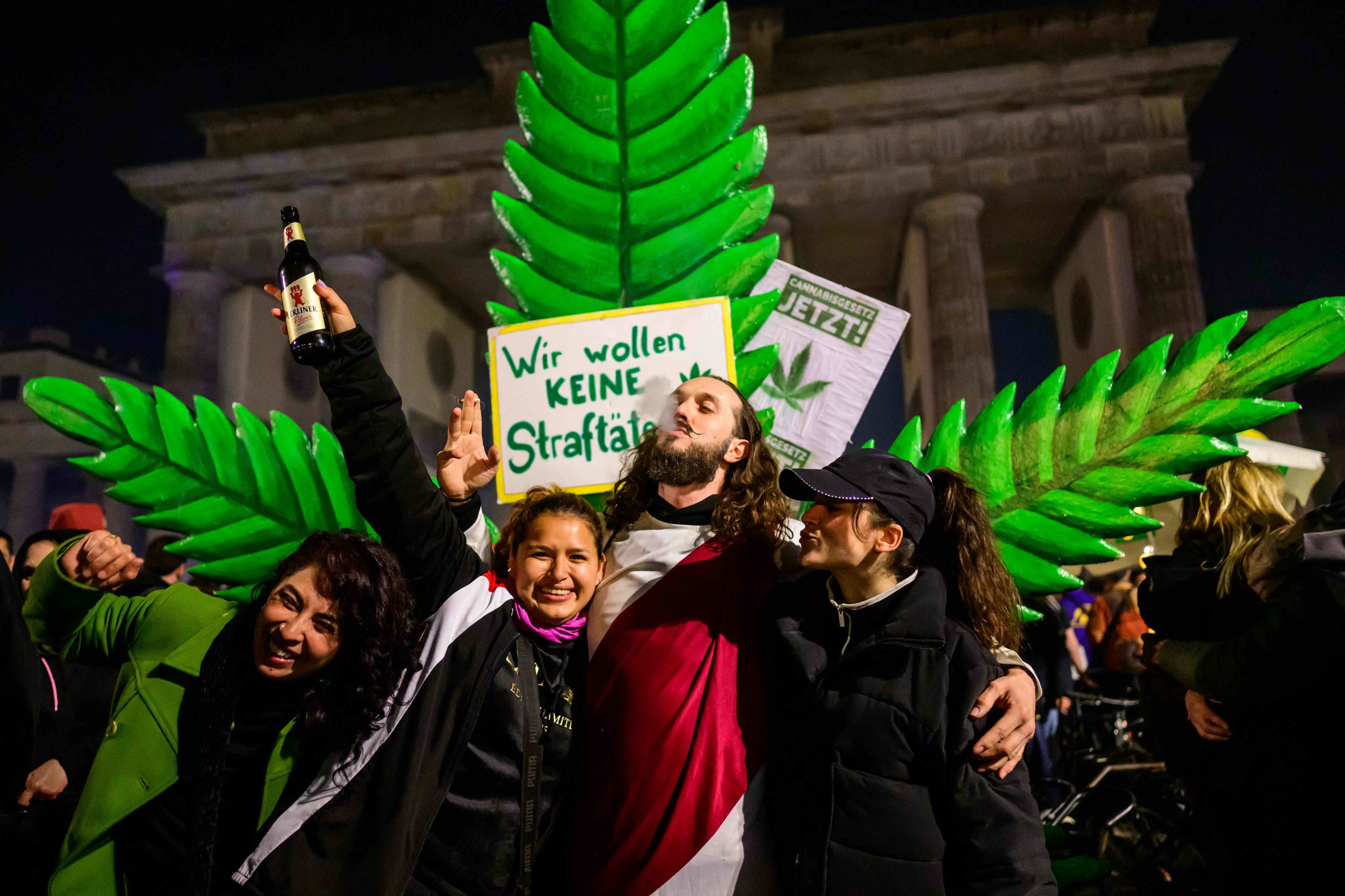 Marijuana smokers celebrate in front of a giant mock marijuana plant outside Berlin’s Brandenburg Gate to mark the coming into force in Germany on April 1, 2024 of a law allowing adults to carry up to 25 grams of dried cannabis and grow up to three marijuana plants at home. Photo: AFP