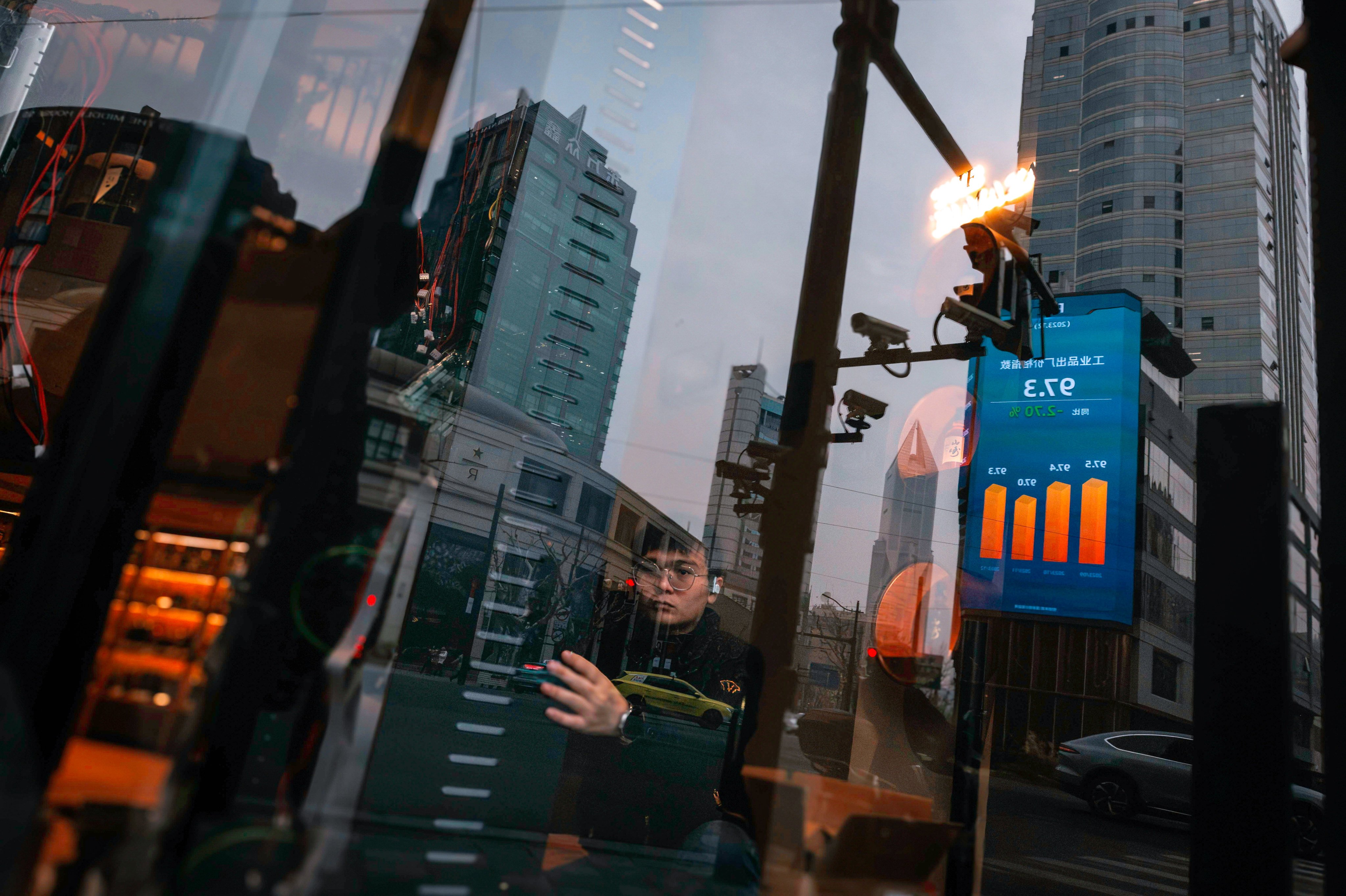 A large screen showing the latest stock exchange and economic data is reflected in a shop window in Shanghai, in this file photo from January. Photo: EPA-EFE