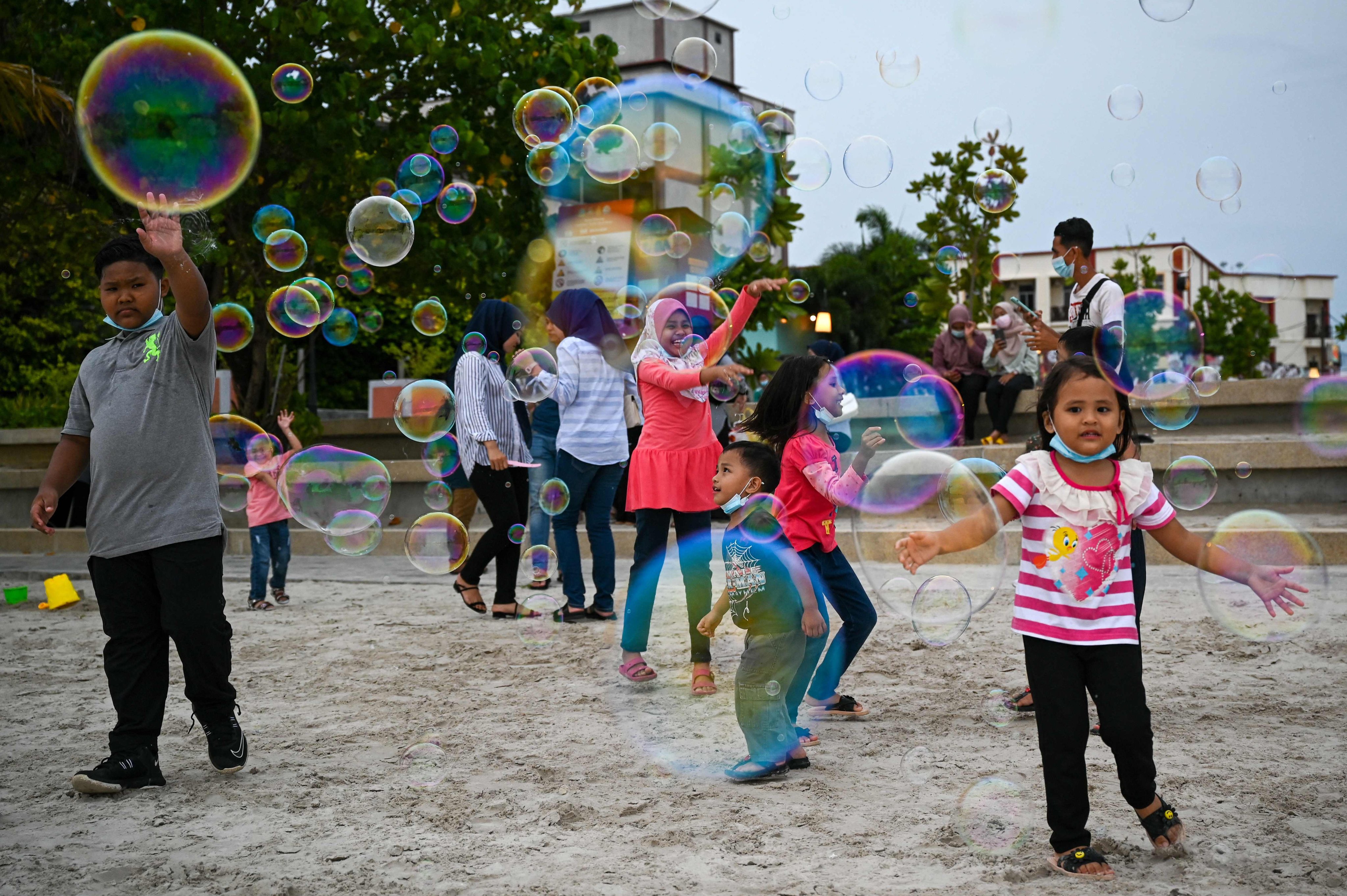 Children play with bubbles at Pantai Cenang in Langkawi on September 15, 2021. The Malaysian cabinet recently rejected a proposal to amend the constitution that would result in certain categories of children having to apply for citizenship. Photo: AFP