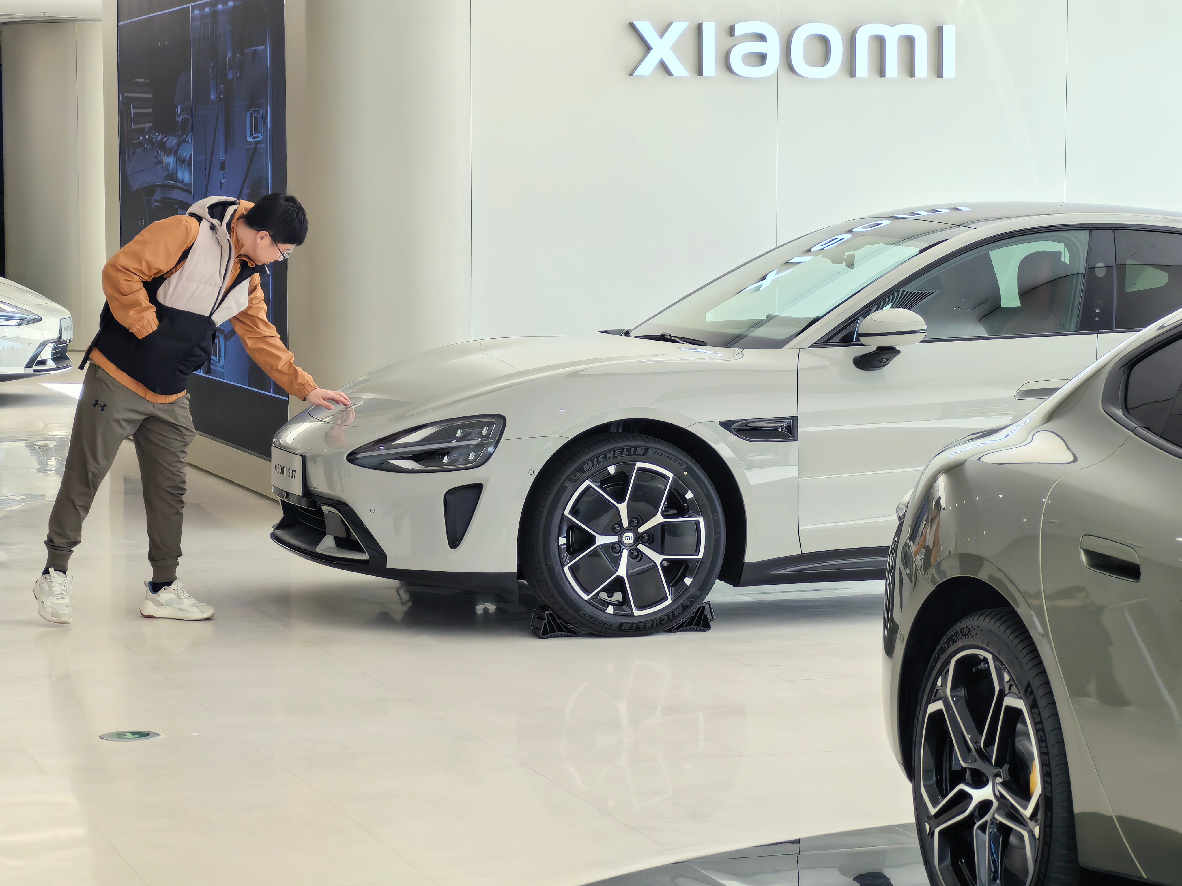 A consumer checks the hood of Xiaomi’s new electric vehicle, the SU7, at the company’s showroom in Beijing on March 30, 2024. Photo: Xinhua