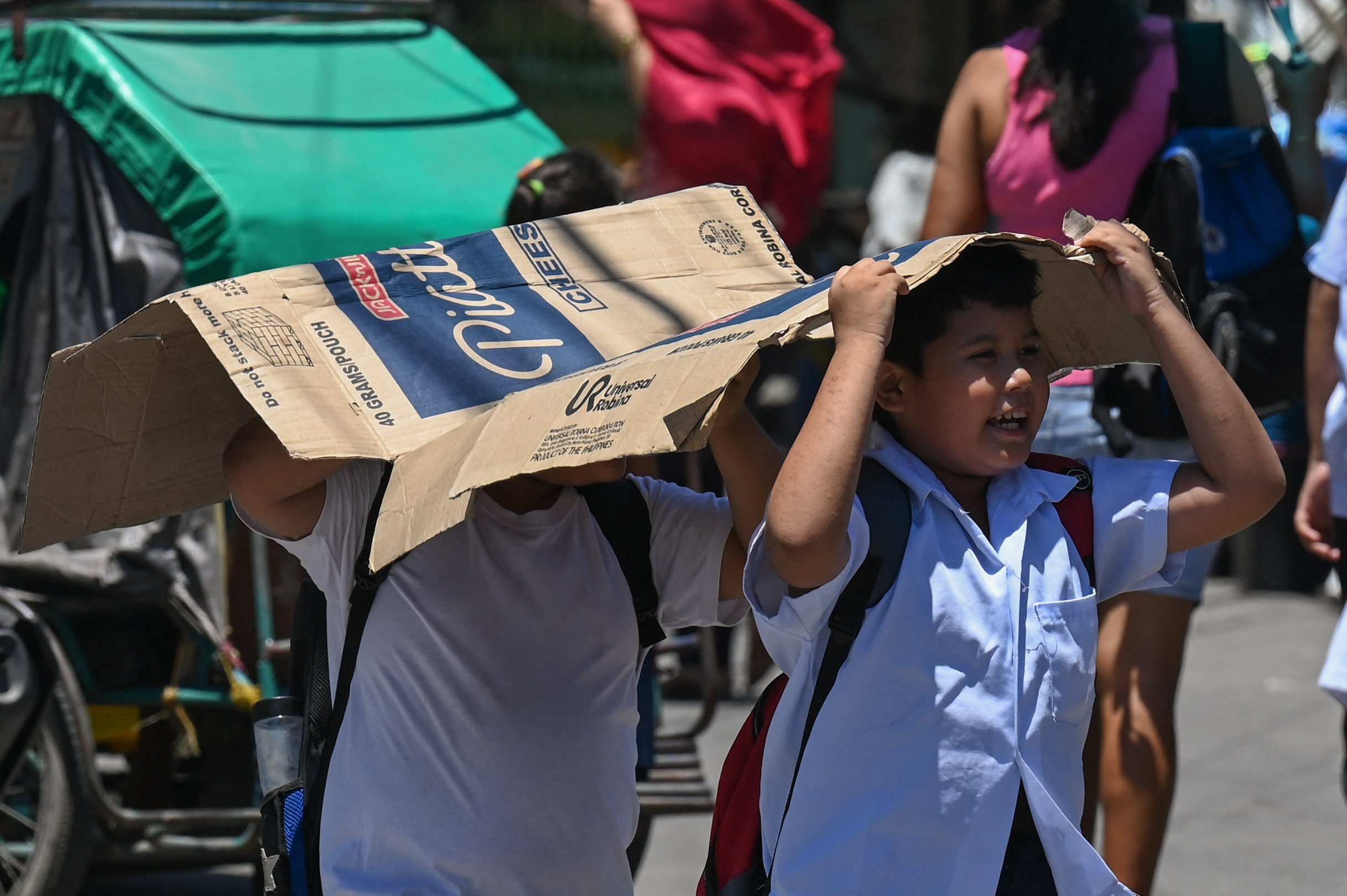 Students use a cardboard to protect themselves from the sun during a hot day in Manila on Tuesday. More than a hundred schools in the Philippine capital shut their classrooms as the tropical heat hit “danger” levels. Photo: AFP