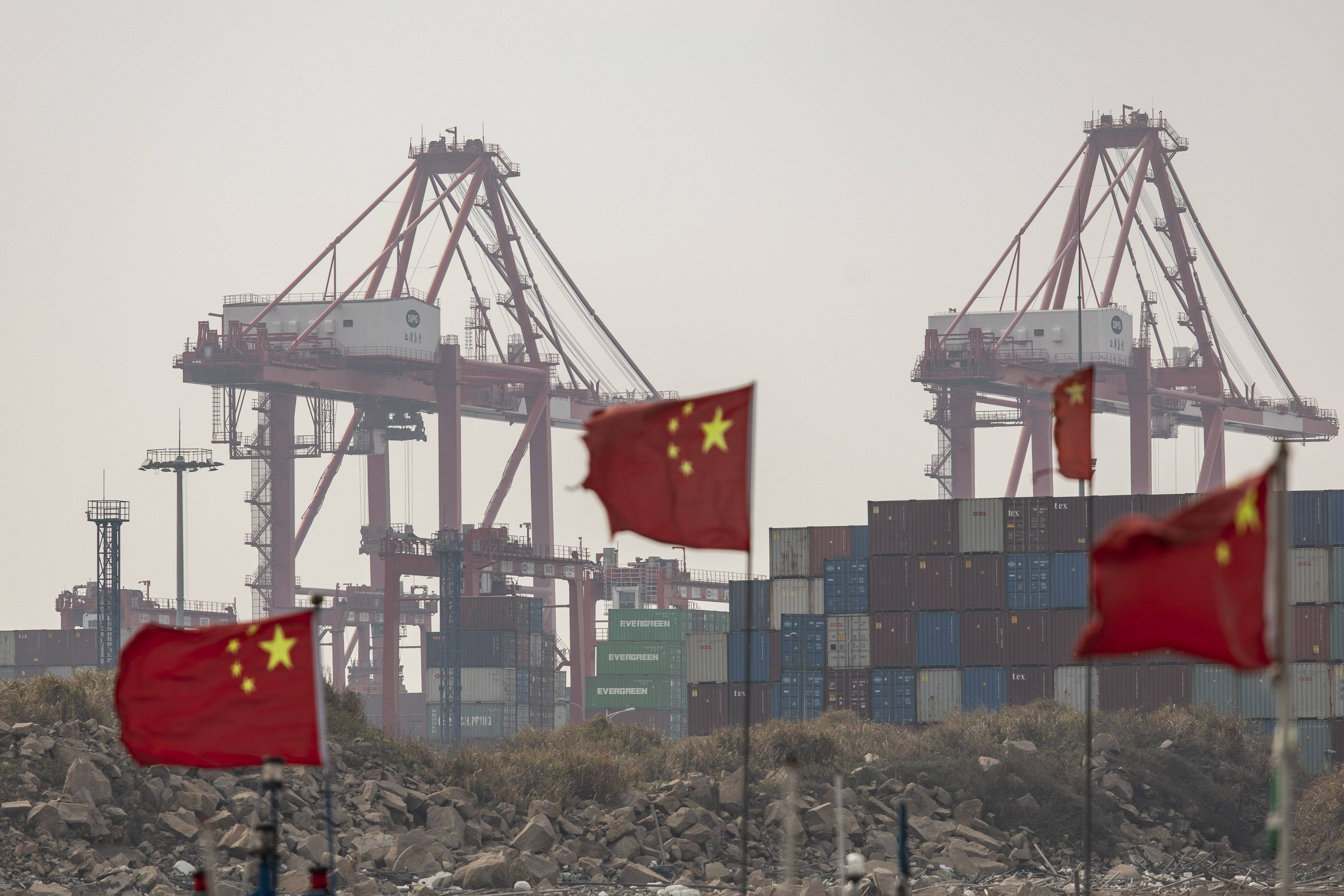 Shipping containers seen beyond Chinese flags on fishing boats near the Yangshan Deepwater Port in Shanghai, China. Photo: Bloomberg