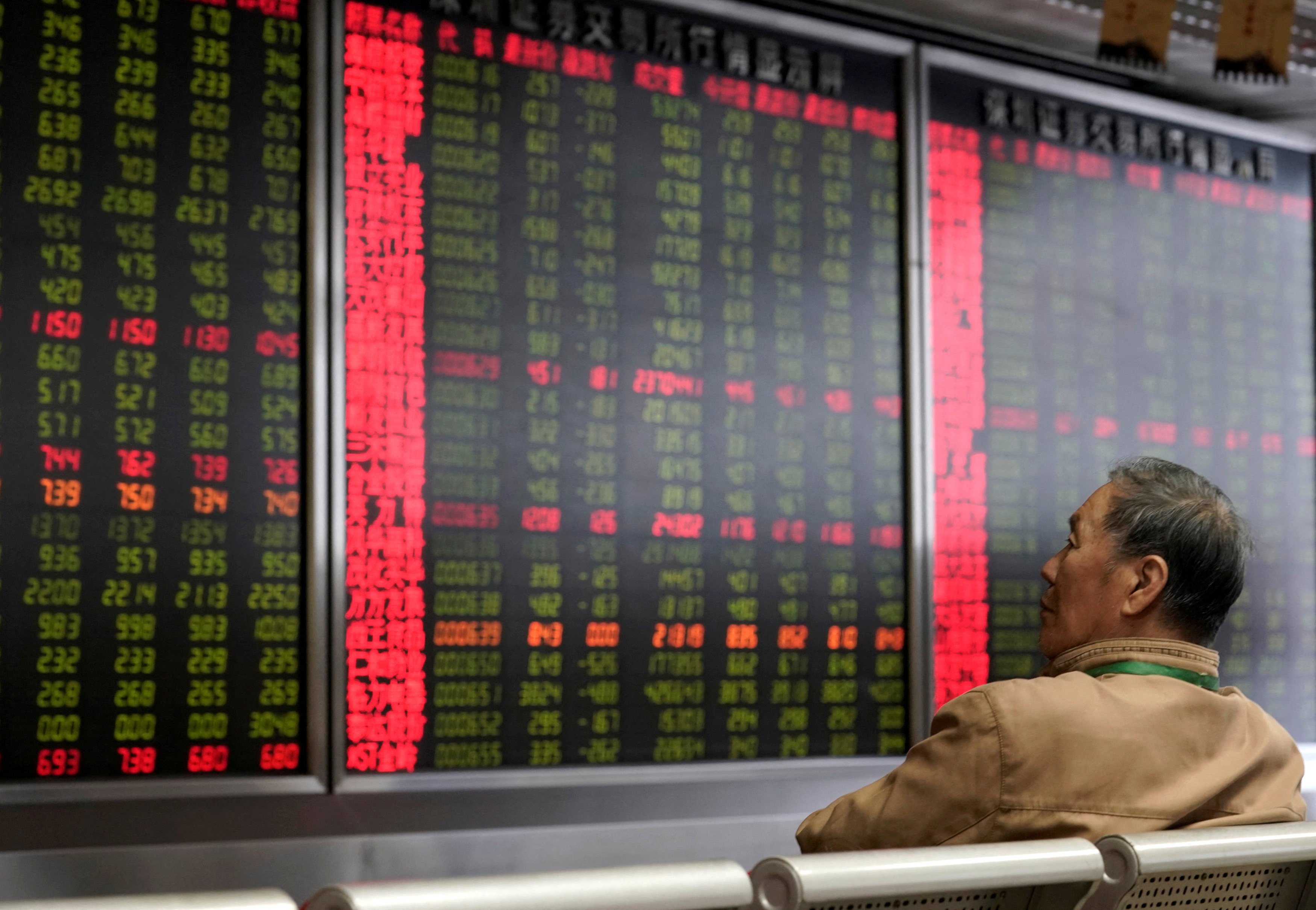 An investor watches a board showing stock information at a brokerage office in Beijing, China. Photo: Reuters