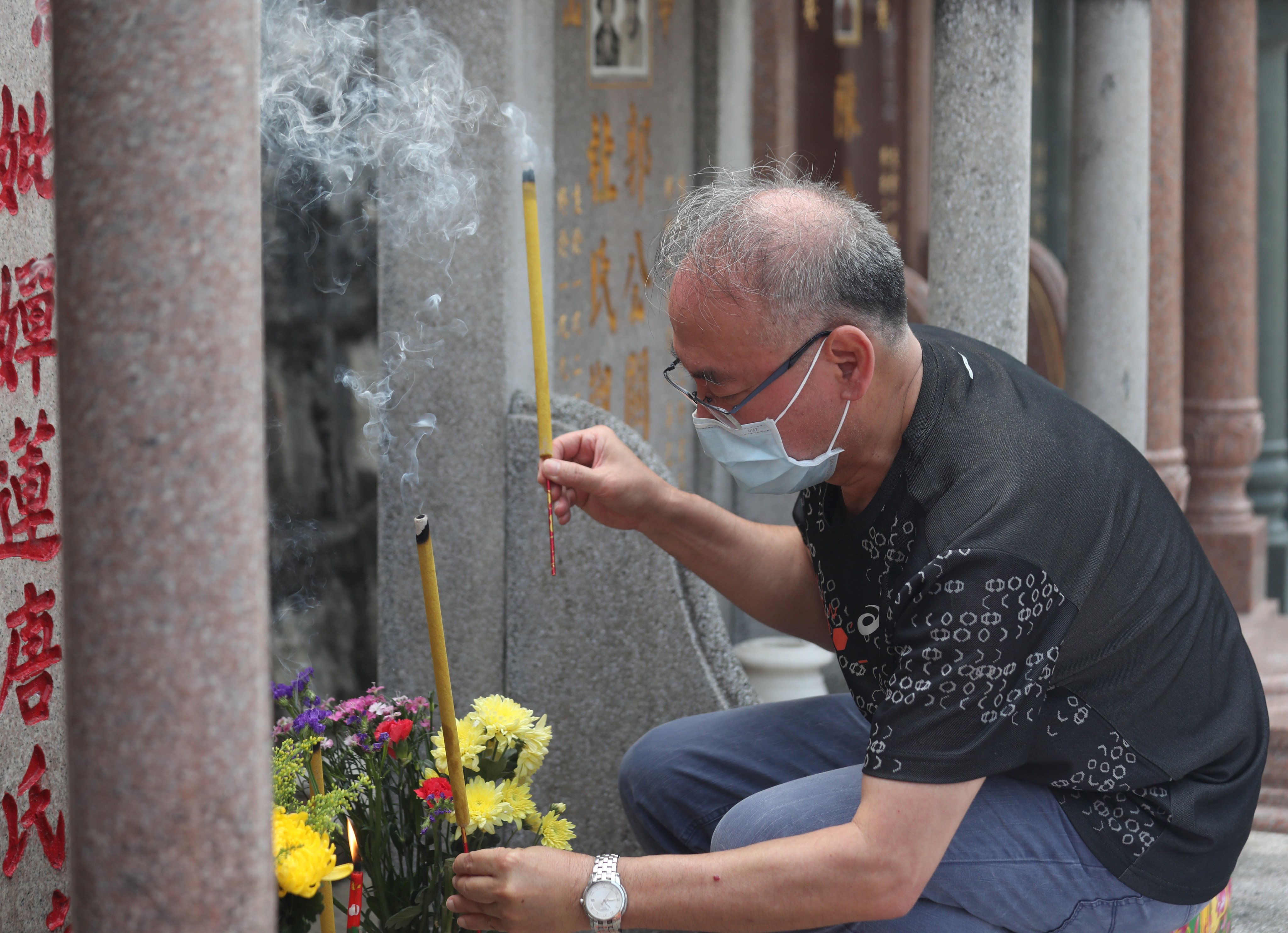 A man lights incense to pay respects to a dead relative at Chai Wan Cemetery in Hong Kong during the Ching Ming Festival. Photo: Xiaomei Chen
