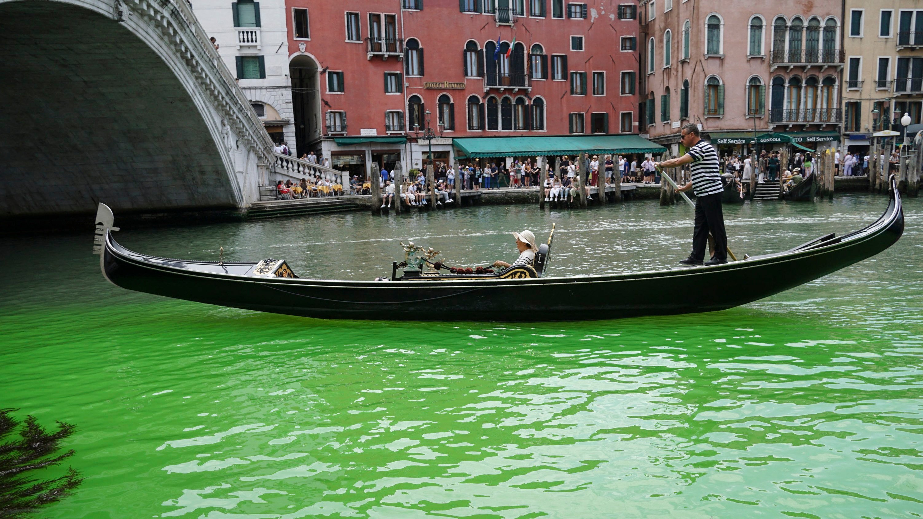 A gondolier propels a gondola along a patch of phosphorescent green liquid seen on the Grand Canal near the Rialto Bridge in Venice. Dozens of raids were conducted with arrests in Italy, Austria, Romania and Slovakia as a result of an investigation into an alleged criminal network. Photo: EPA-EFE
