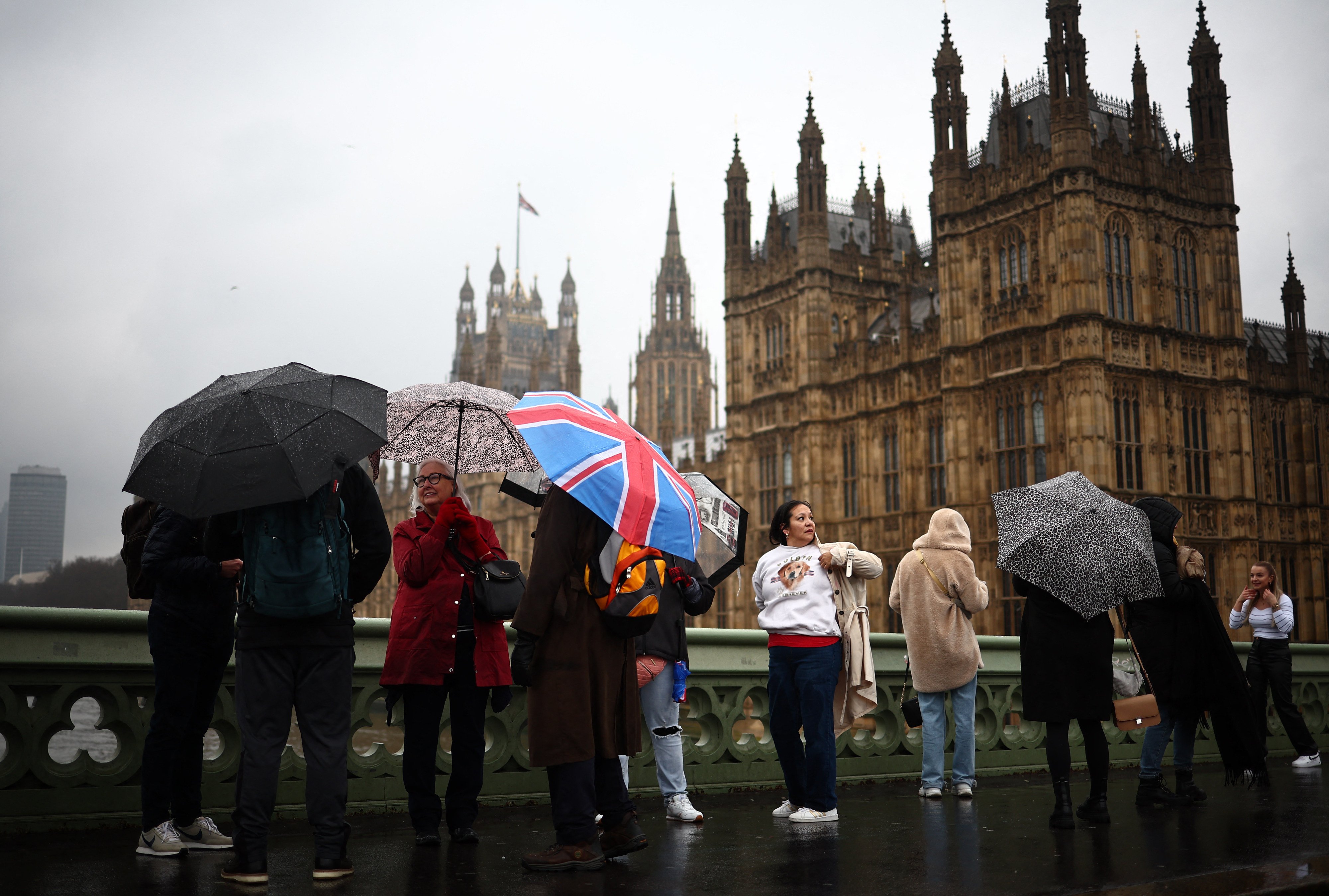 Tourists shelter from the rain as they walk over Westminster Bridge, in London, the UK, on March 10, 2024. This winter the UK has endured relentless rain, while in Hong Kong, unseasonably warm weather saw March temperatures hit their highest ever. Photo: AFP