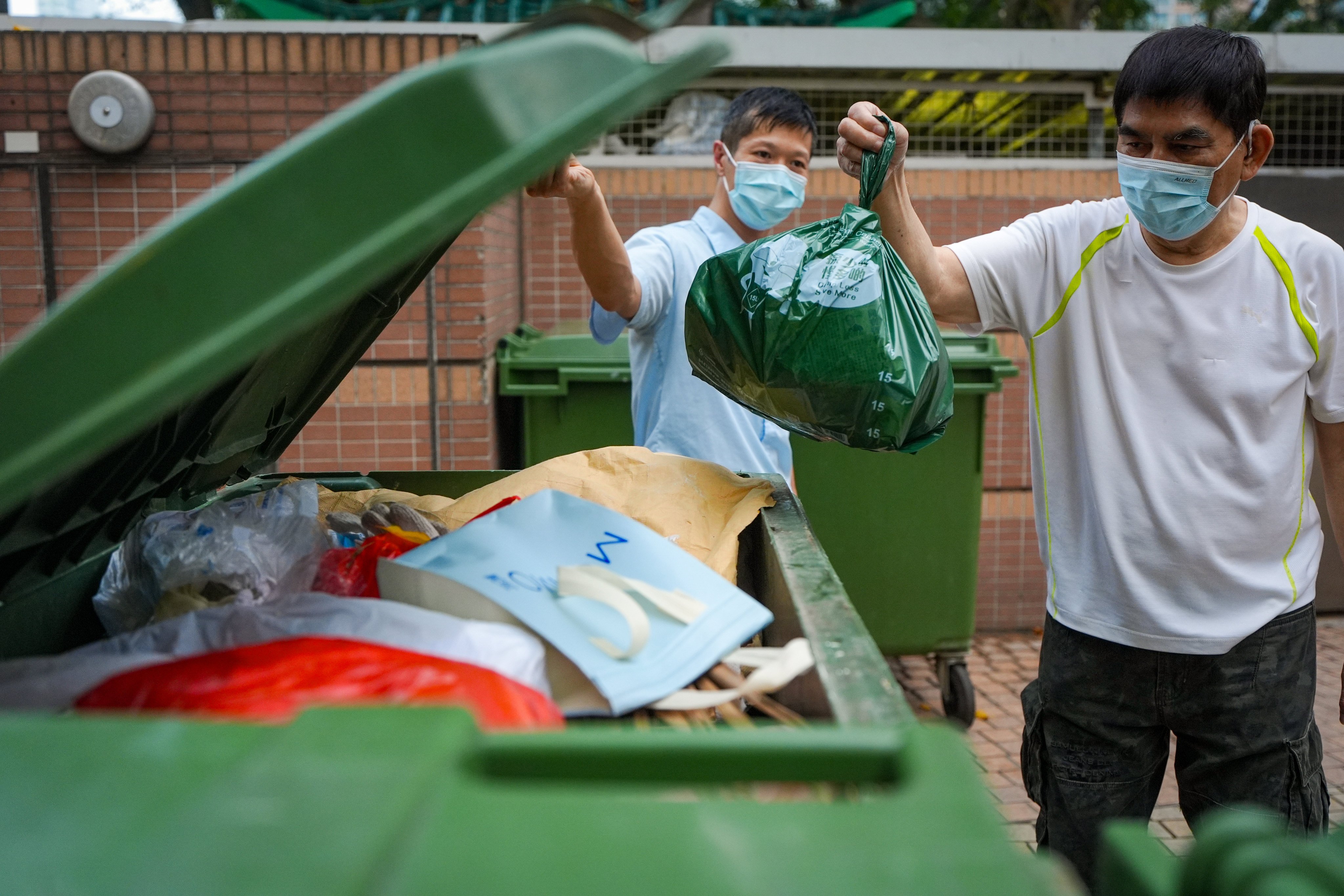A resident dumps an approved green trash bag at On Ning Lau, Moon Lok Dai Ha, in Tsuen Wan, which is taking part in the trial run of the waste-charging scheme. Photo: Eugene Lee
