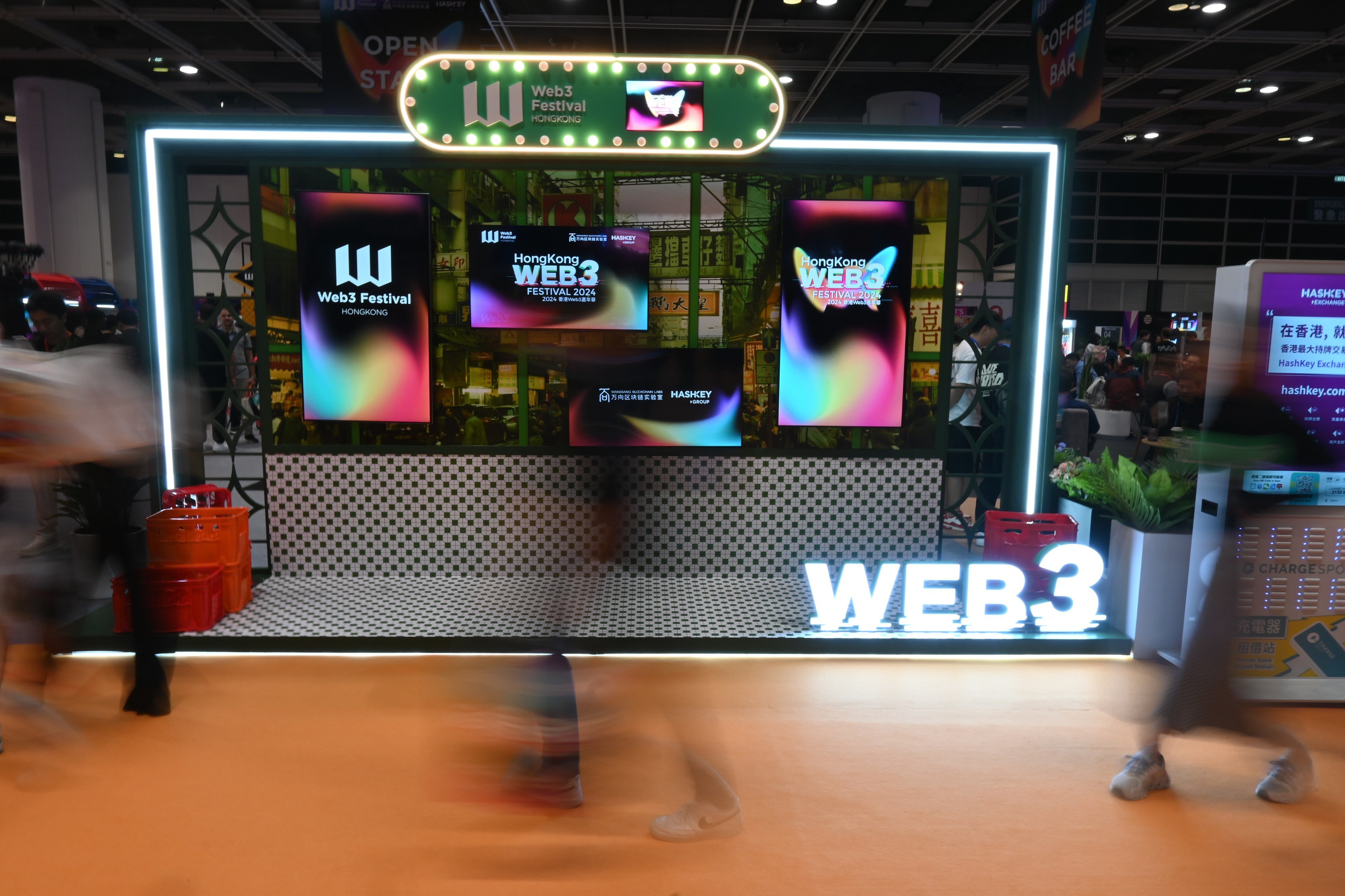 People pass by a display for the Hong Kong Web3 Festival at the Convention and Exhibition Centre in Wan Chai on April 6, 2024. Photo: SCMP / Matt Haldane