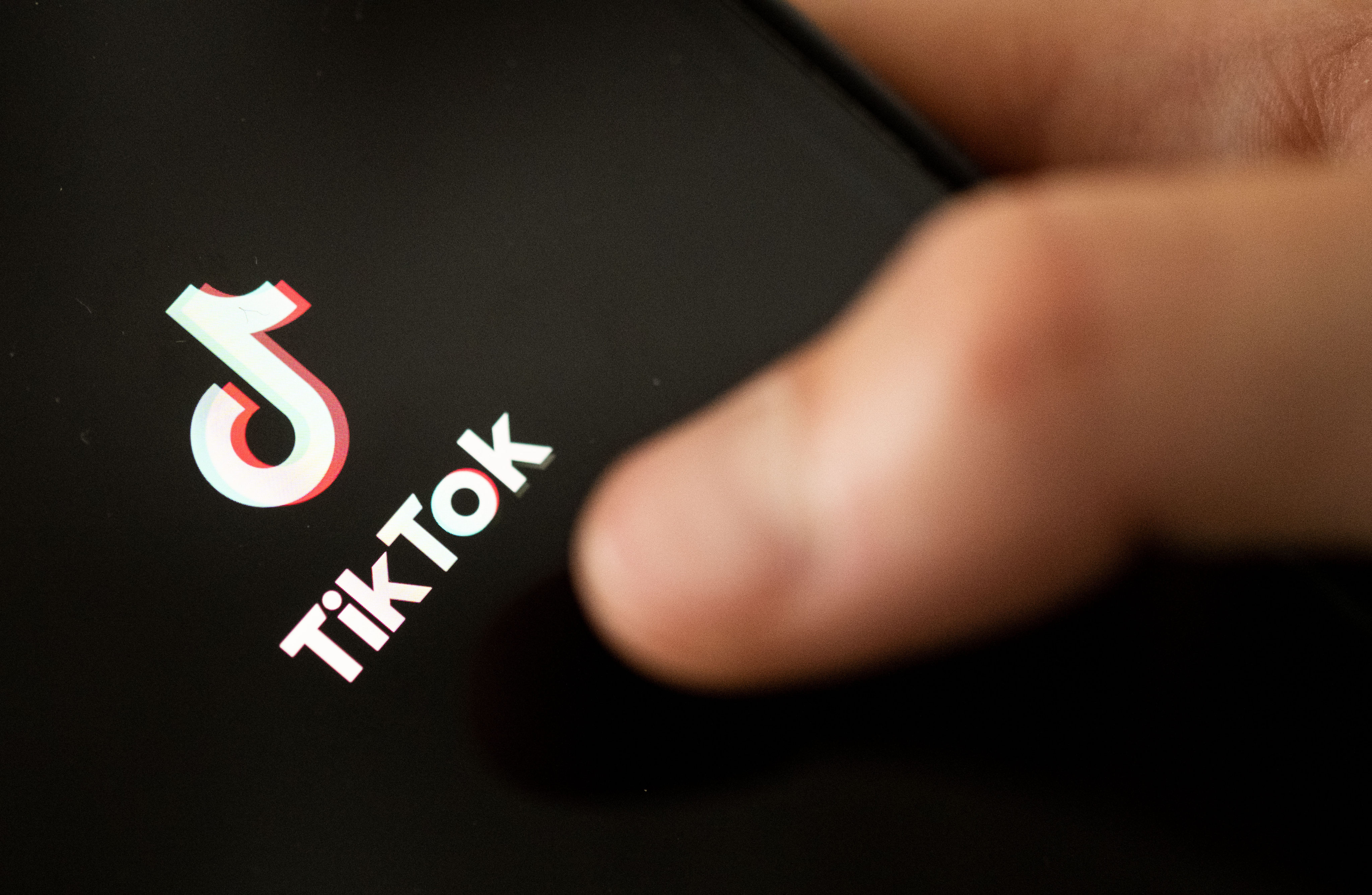 A teenager taps the TikTok logo on a smartphone. Photo: dpa