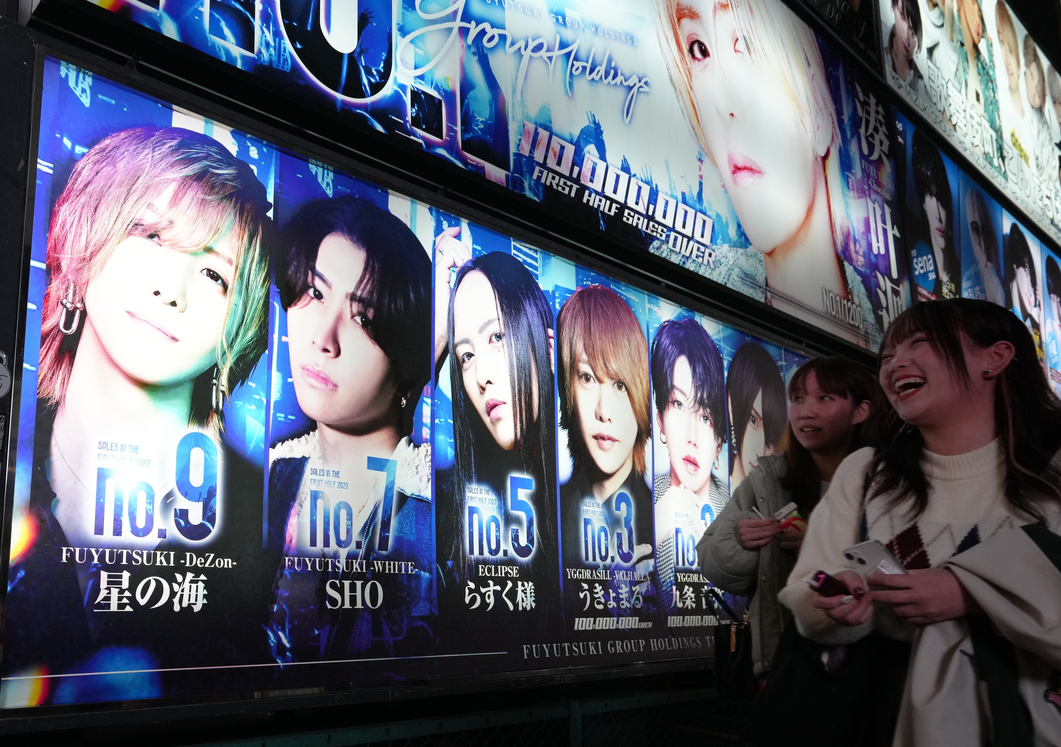 Women walk past an advertisement for a “host club” in the Shinjuku ward of Tokyo in December. Photo: EPA-EFE