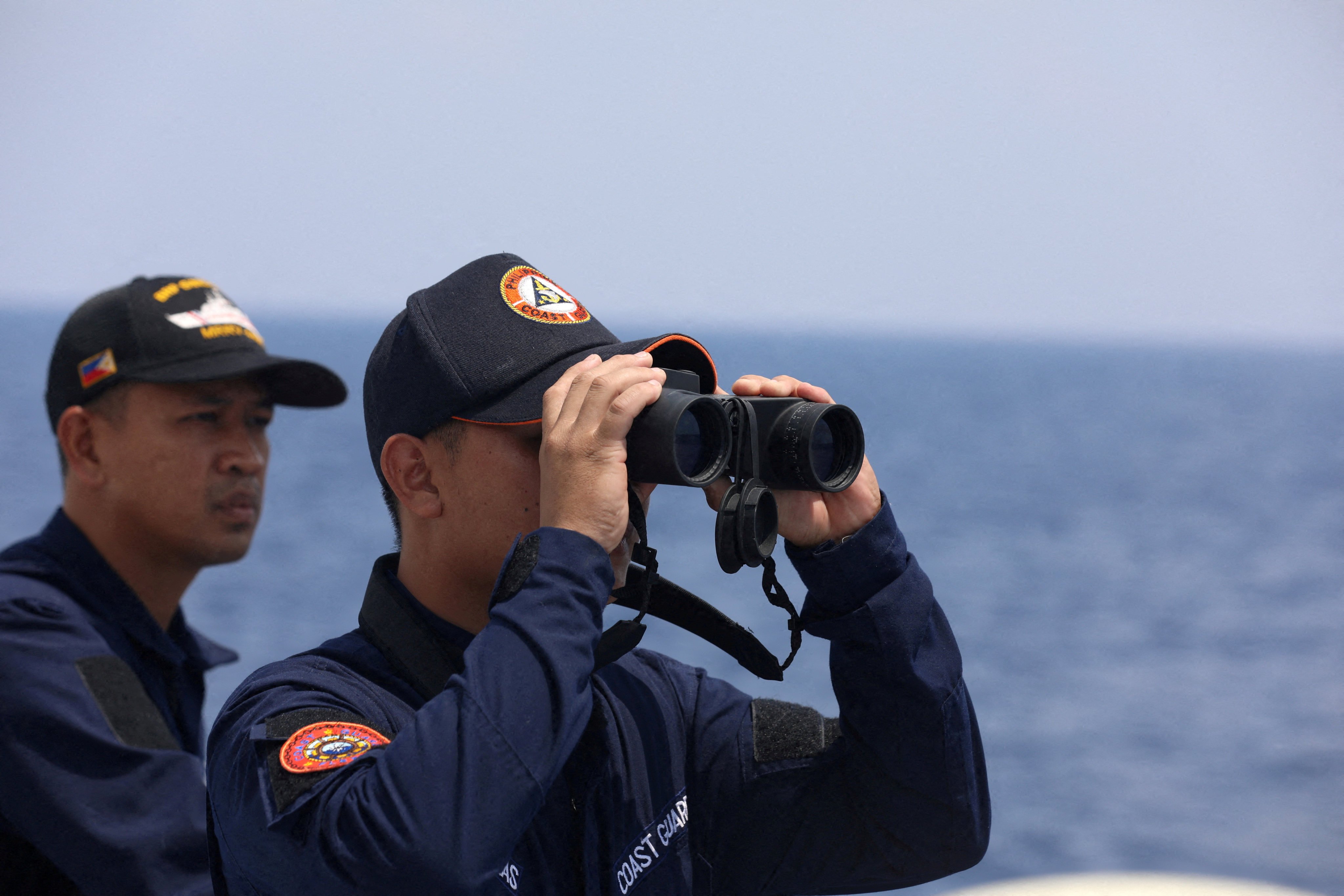 A Philippine Coast Guard personnel looks through binoculars while conducting a resupply mission for Filipino troops stationed at a grounded warship in the South China Sea in October 2023. Photo: Reuters