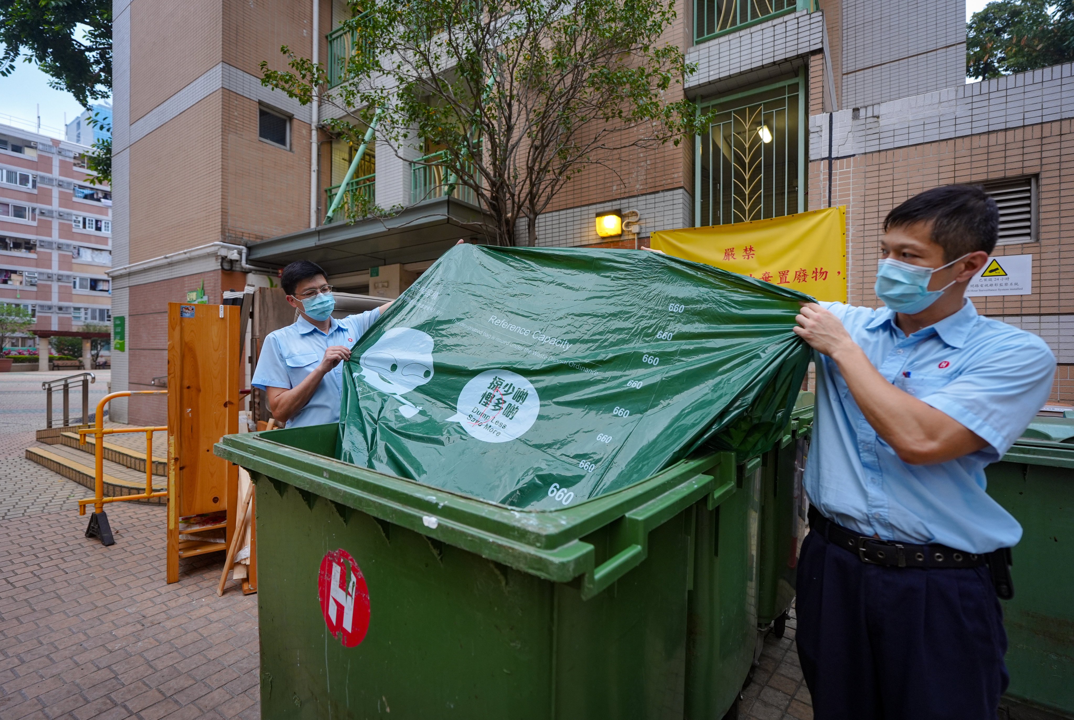 Property management officers display an approved green trash bag in Tsuen Wan. The government this month rolled out a trial run for the scheme at 14 locations. Photo: Eugene Lee