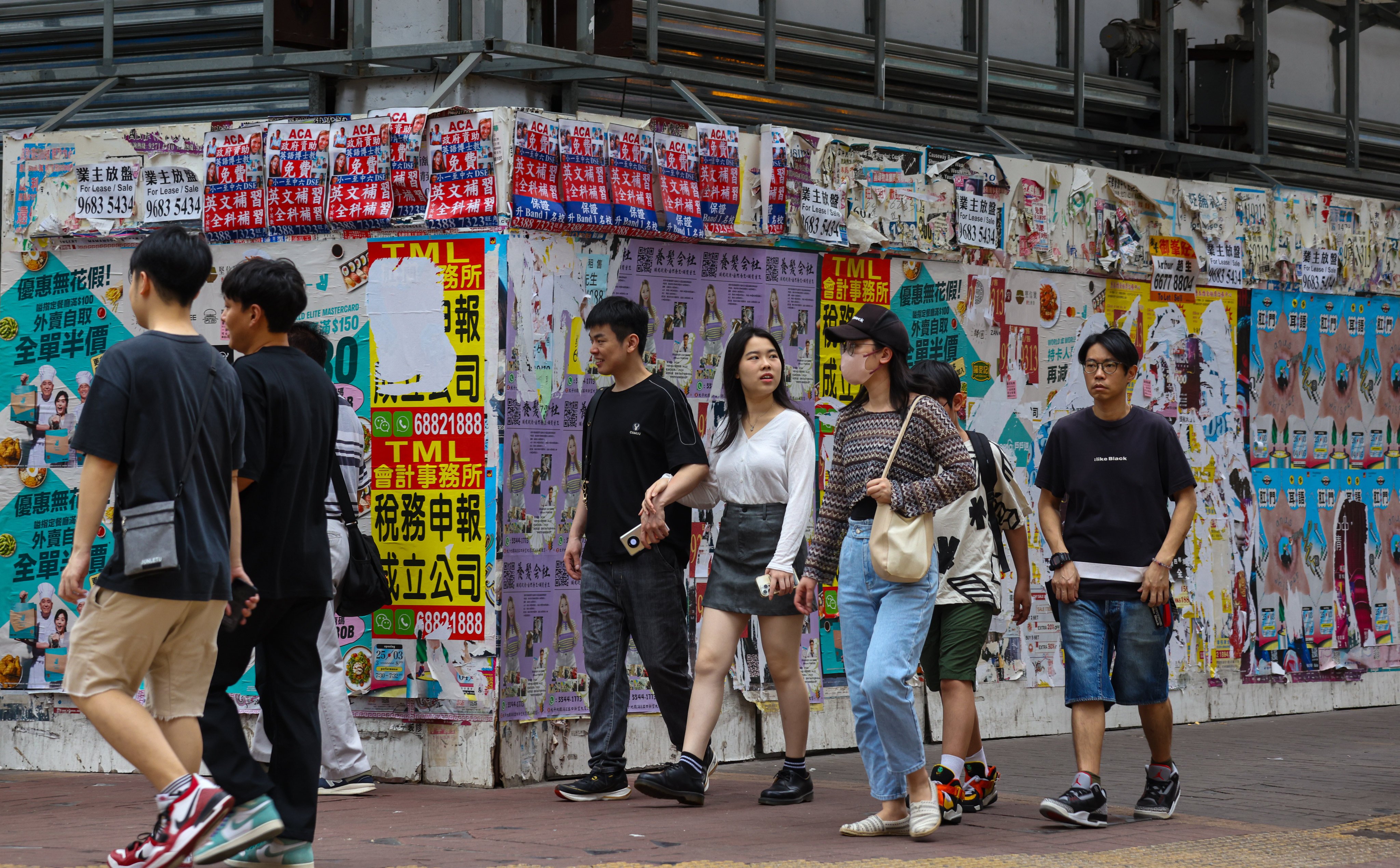Pedestrians walk past a boarded-up shop as retail and travel sector experts warn poor pay rises could hurt the industries. Photo: Yik Yeung-man