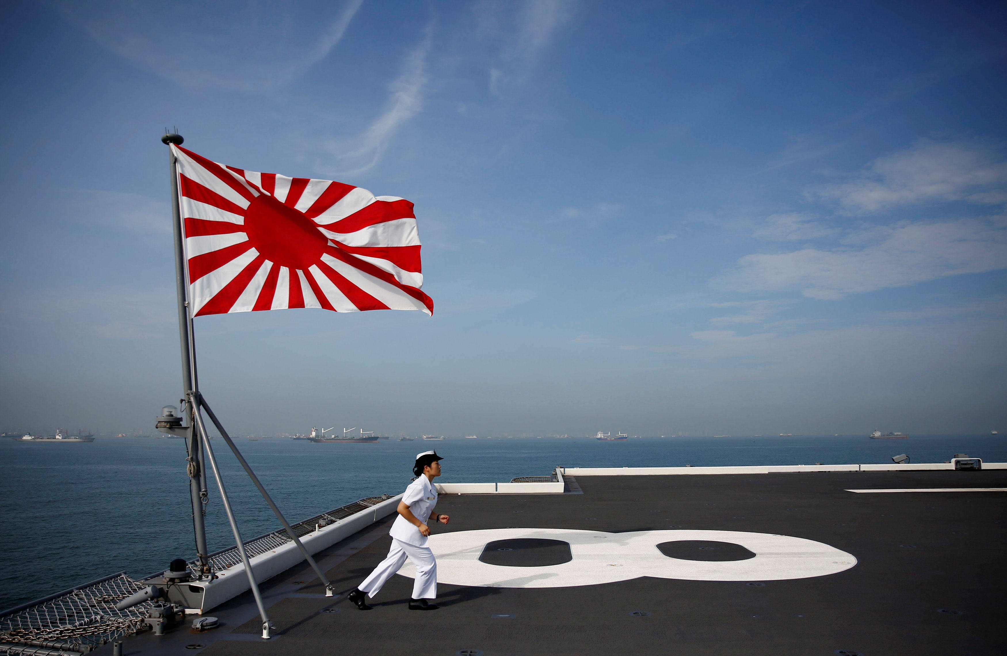 A navigator runs back to her post after raising the Rising Sun Flag, the Japanese naval ensign, aboard the Kaga in 2018 while it was still a helicopter carrier. Photo: Reuters