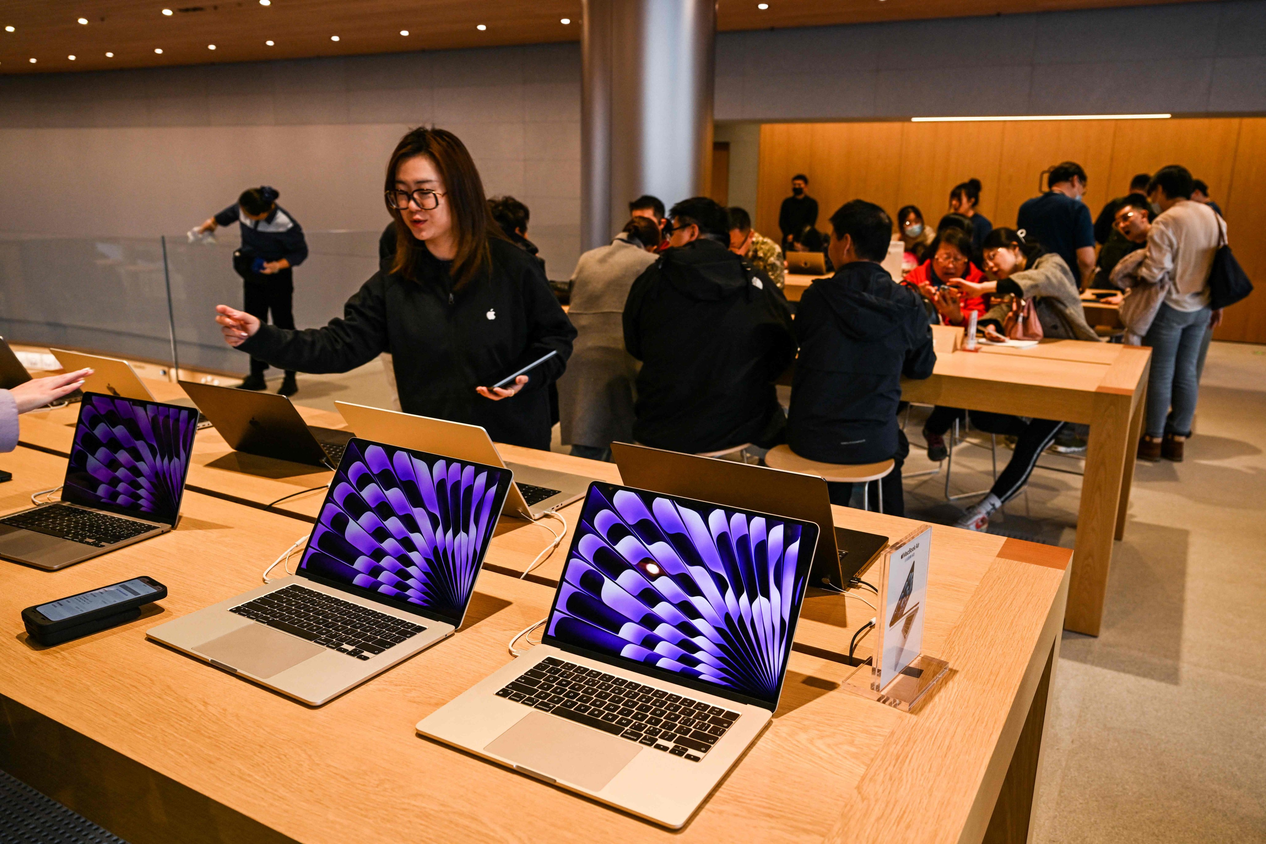 An employee gestures beside Mac computers on display at an Apple Store in Shanghai’s Jing’an district, March 26, 2024. Photo: AFP