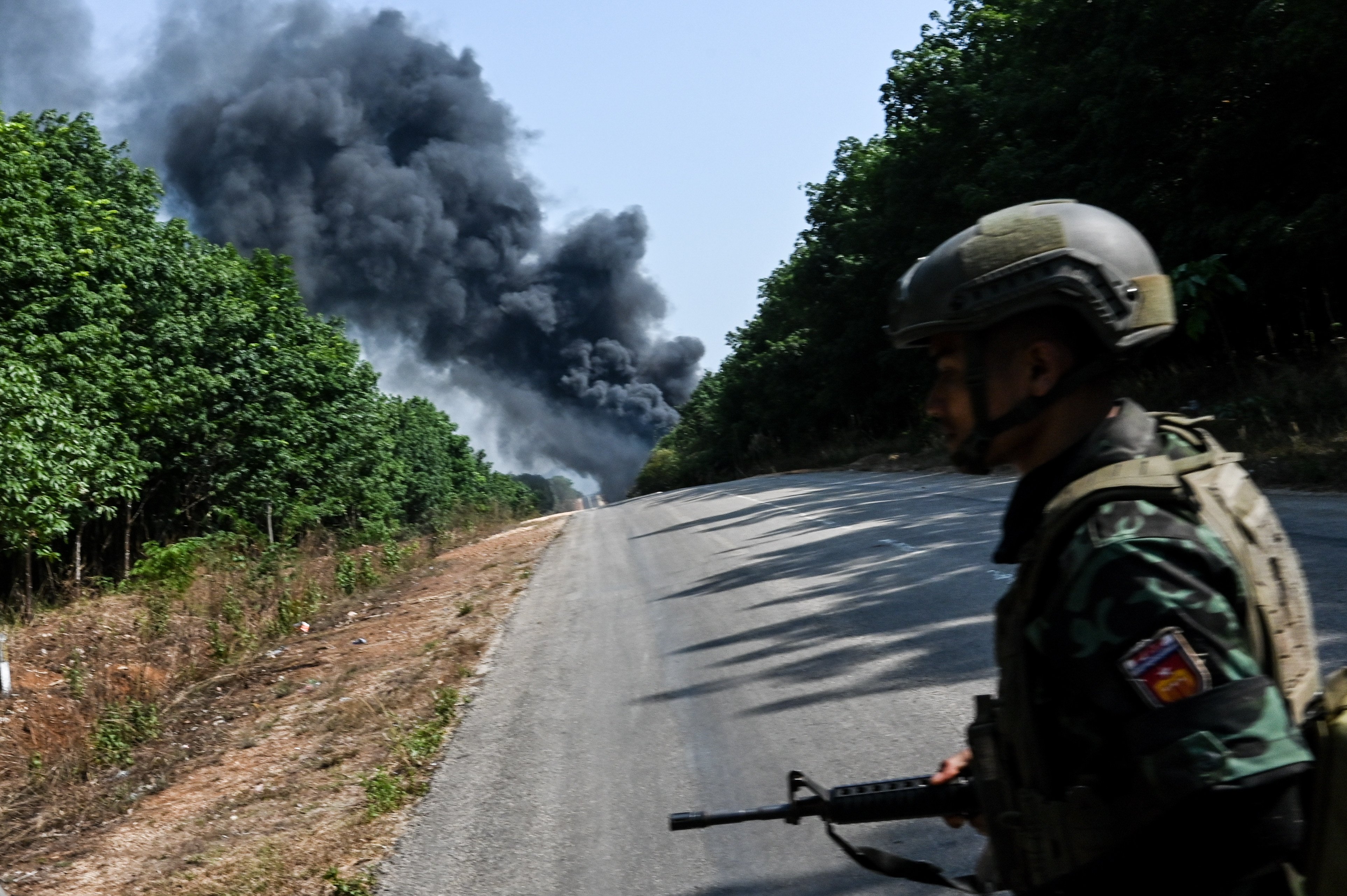 A member of the Myanmar People’s Defence Forces at a rebel-held checkpoint near Dawei city looks on as smoke rising from a junta air strike. Photo: Khu Sam