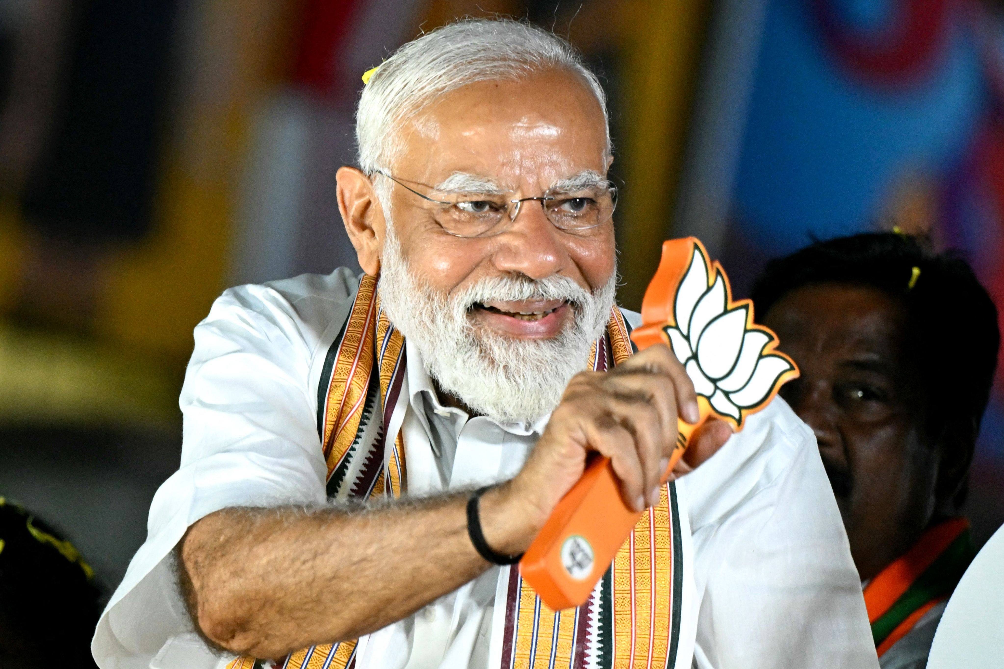 Narendra Modi, India’s prime minister and leader of the ruling BJP, holds the party symbol during a campaign event in Chennai on Tuesday. Photo: AFP