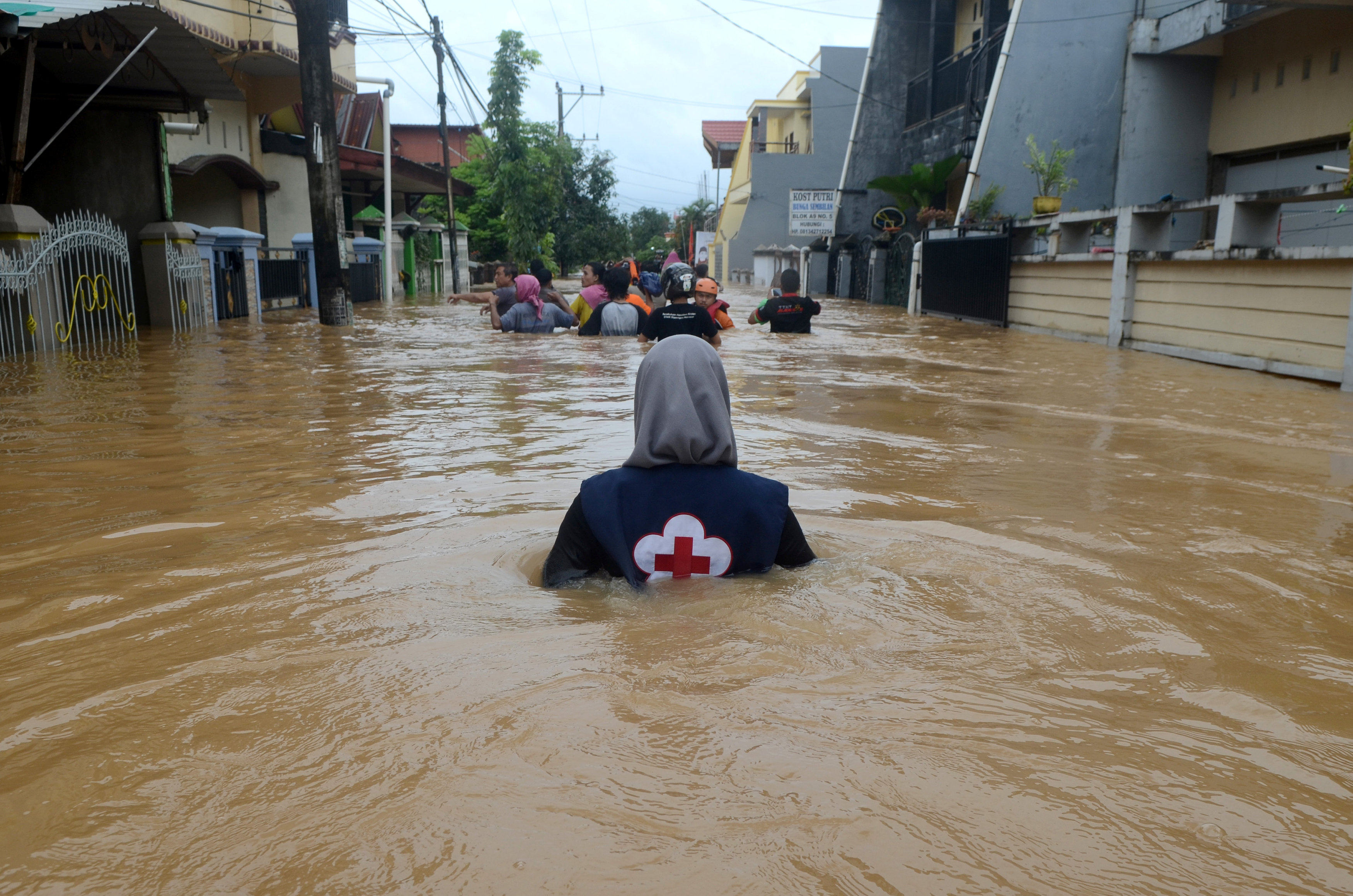 A volunteer wades through floods at a residential area in Makassar, South Sulawesi, Indonesia, on January 23, 2019. Photo: Antara Foto/Sahrul Manda Tikupadang/ via Reuters 