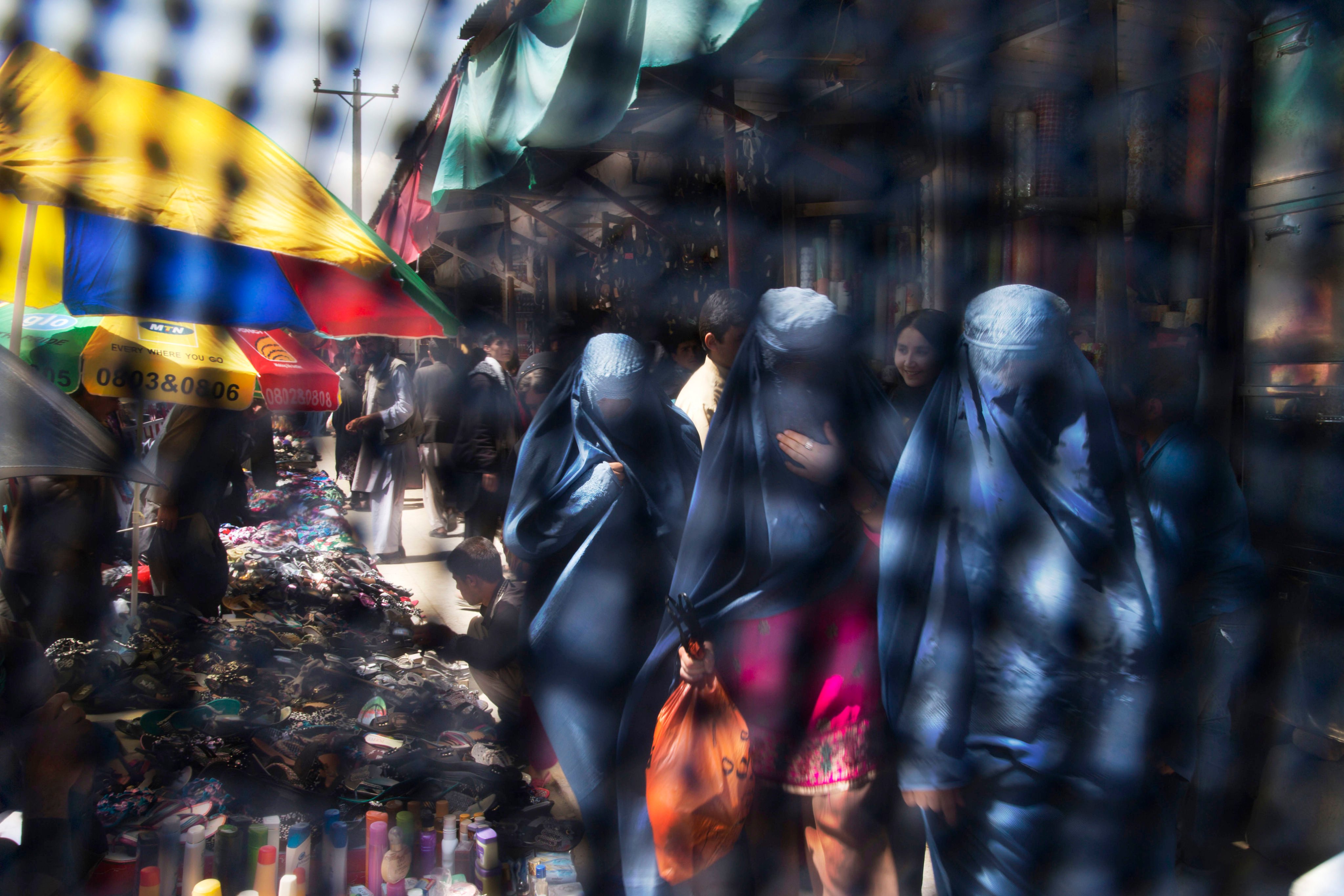 Seen through the eye grid of a burqa, women walk through a market in Kabul. The Taliban – who say they respect women’s rights in line with their interpretation of Islamic law and local customs – have closed girls’ high schools and placed travel restrictions on women without a male guardian and restricted access to parks and gyms. Photo: AP