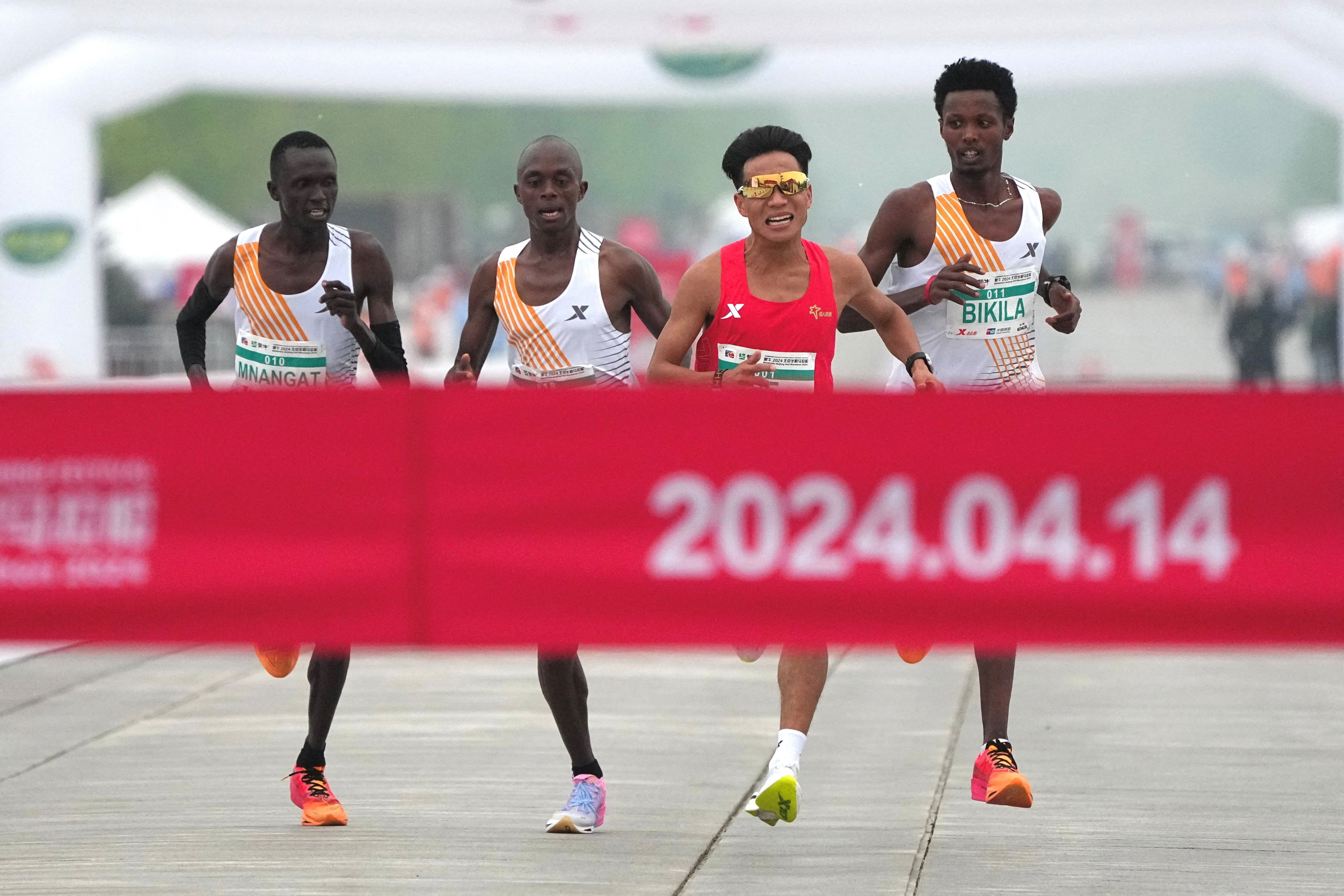 Chinese runner He Jie heads for the line ahead of (from left) Kenyans Willy Mnangat and Robert Keter, and Ethiopian Dejene Hailu Bikila. Photo: Reuters