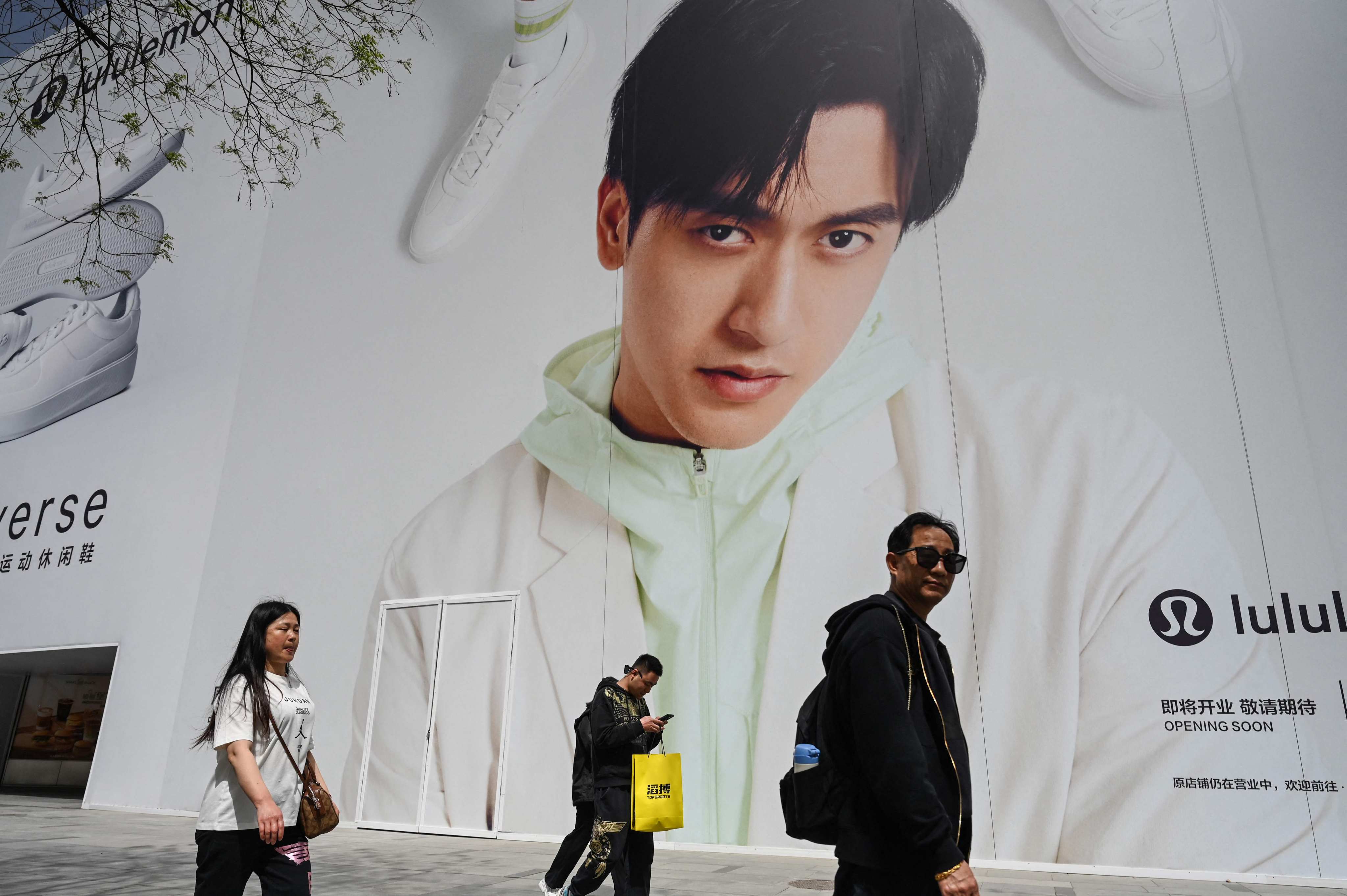 People walk past a billboard showing Chinese Formula One driver Zhou Guanyu at a shopping centre complex in Beijing. Photo: AFP