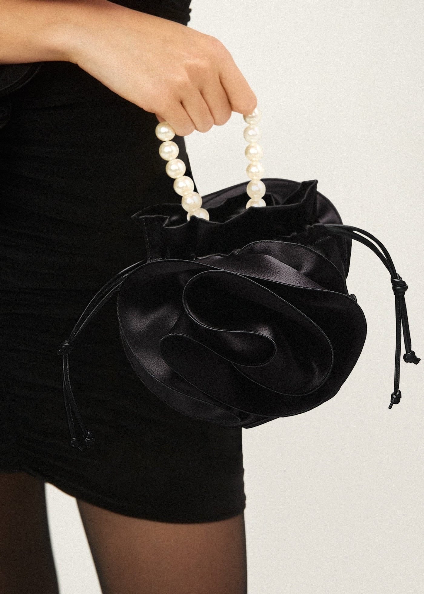 Discover the understated elegance of rose-shaped bags this spring, with unique creations from Burberry, Magda Butrym, and Thom Browne. These floral-inspired designs offer a refreshing twist to your evening essentials. Pictured: Pearl Magda bag in black satin, by Magda Butrym. Photos: Handout