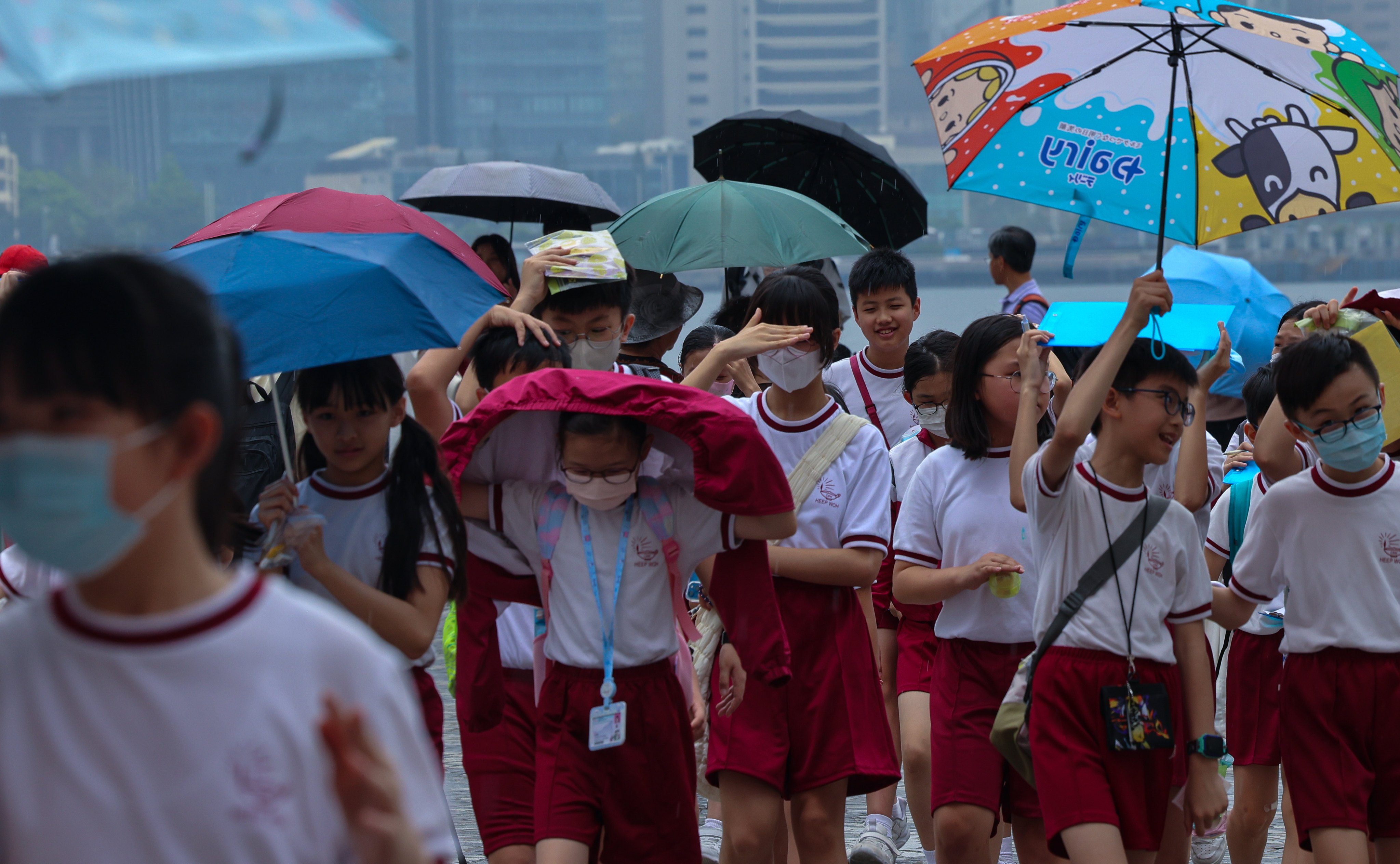 Children brave the wind and rain at Tsim Sha Tsui waterfront. The Observatory issued the first amber rainstorm warning of the year at 1pm on Thursday. Photo: Jelly Tse