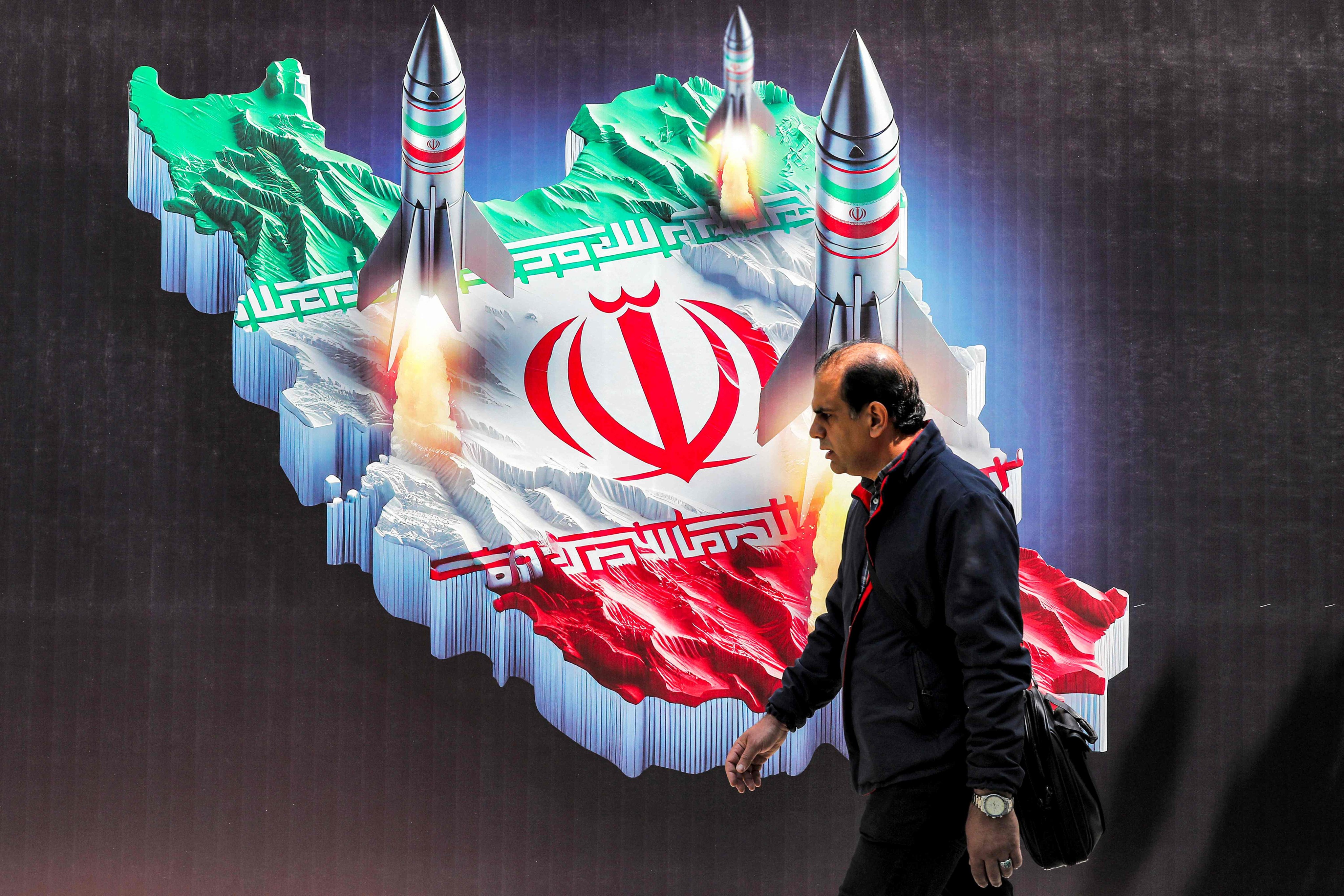  A man walks past a banner depicting missiles launching from a representation of the map of Iran coloured with the Iranian flag in central Tehran on April 15. Iran has urged Israel not to retaliate militarily to an unprecedented attack, which Tehran presented as a justified response to a deadly strike on its consulate building in Damascus. Photo: AFP