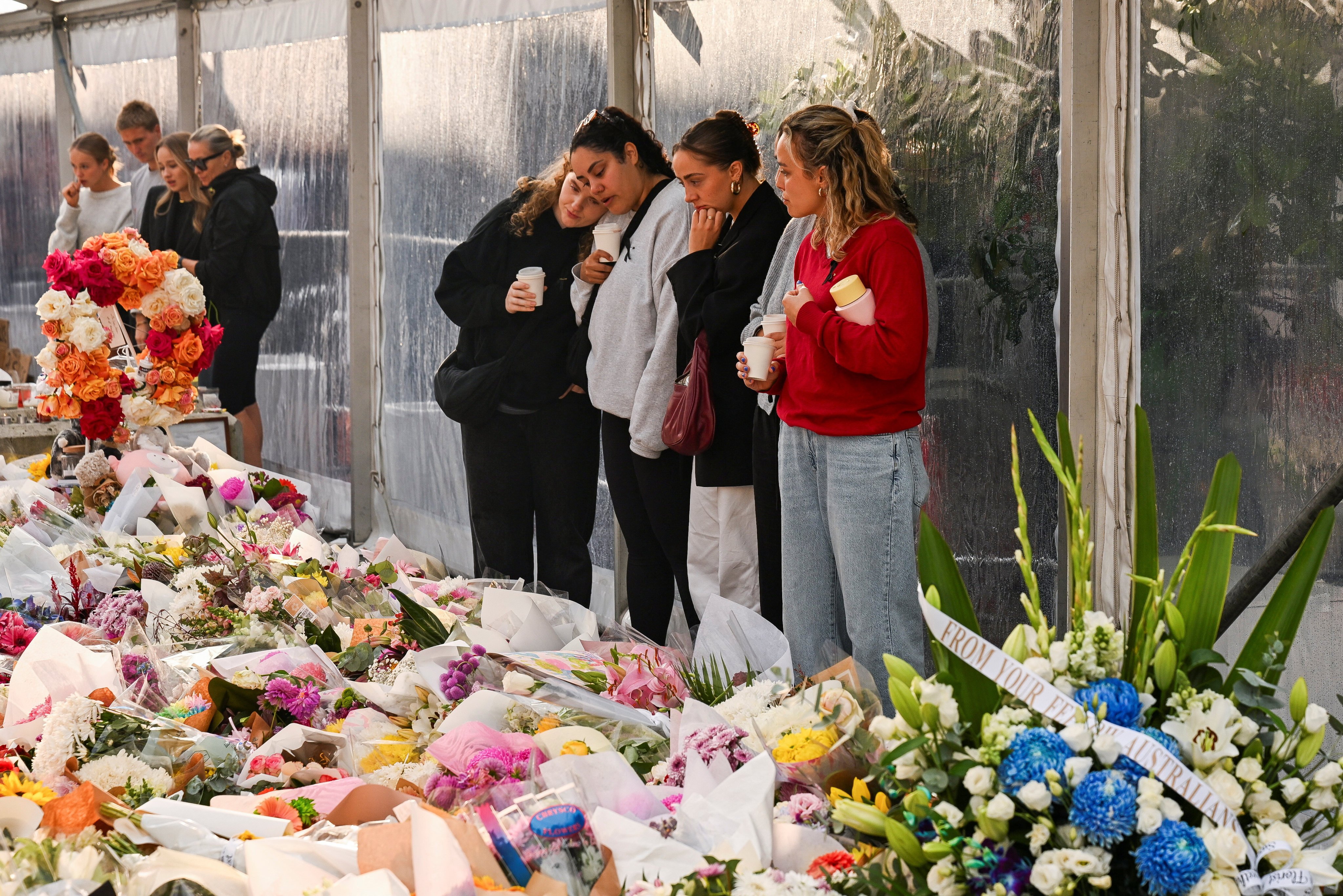 People on Thursday view the floral tributes for victims of the stabbing attacks which killed several people at the Westfield Bondi Junction shopping centre in Sydney, Australia. Photo: Reuters