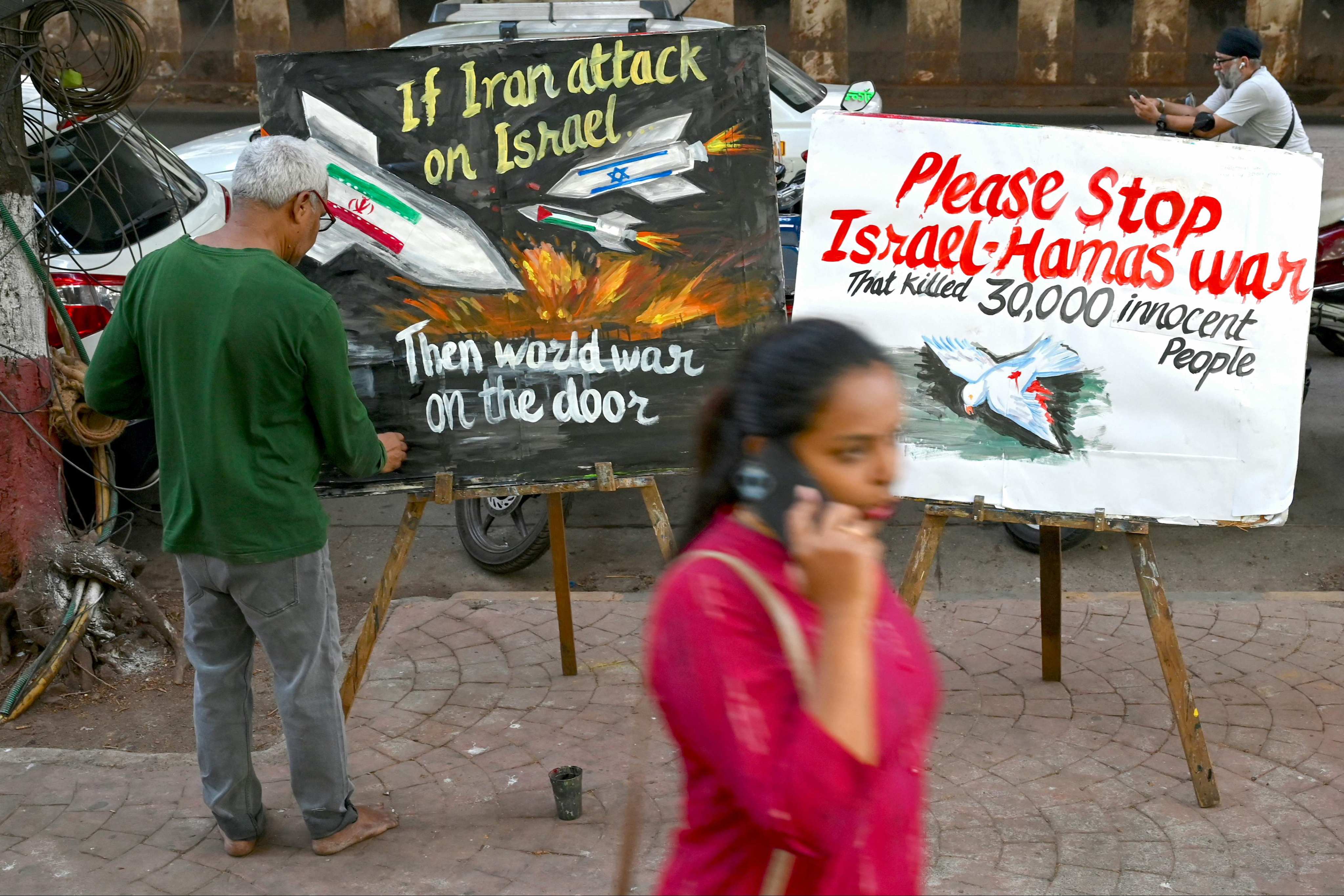 An artist painting messages on a street in Mumbai calling for an end to the unrest between Palestine, Israel and Iran on April 13, 2024. Photo: AFP